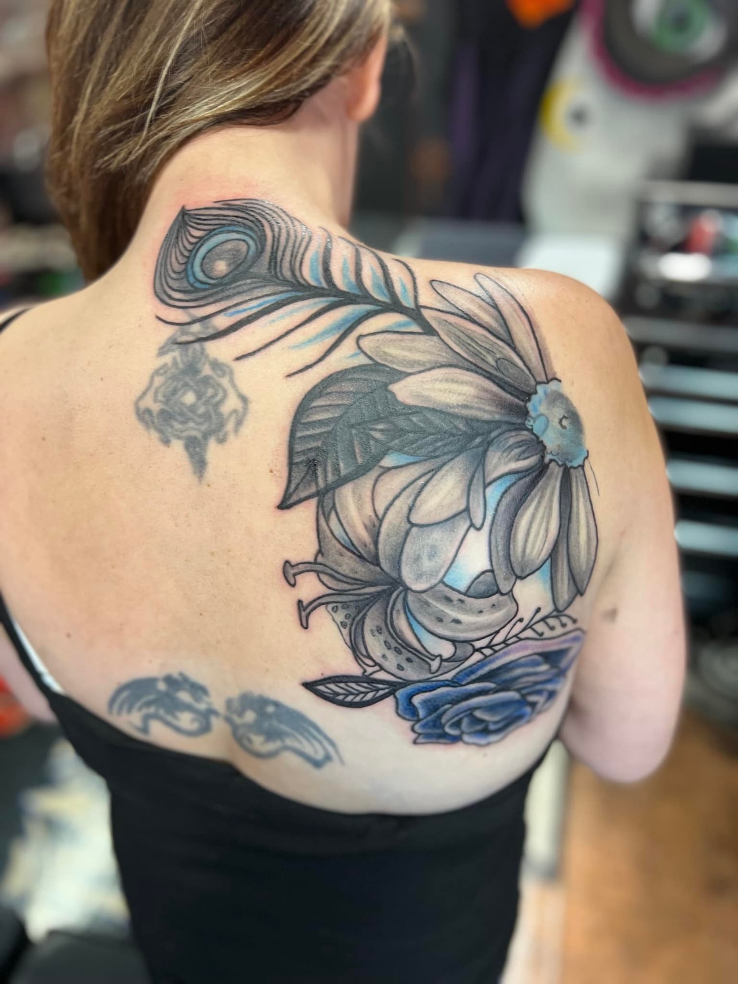 Peacock feather and flower neo-traditional tattoo on the back by @juiceinkythings