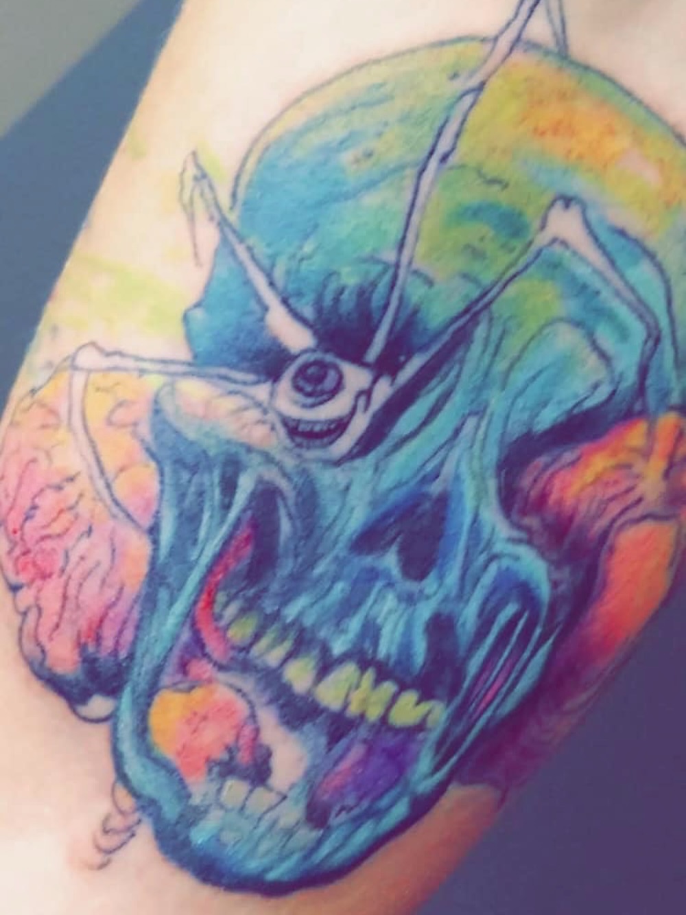 Grinning skull watercolor tattoo on the forearm by @juiceinkythings