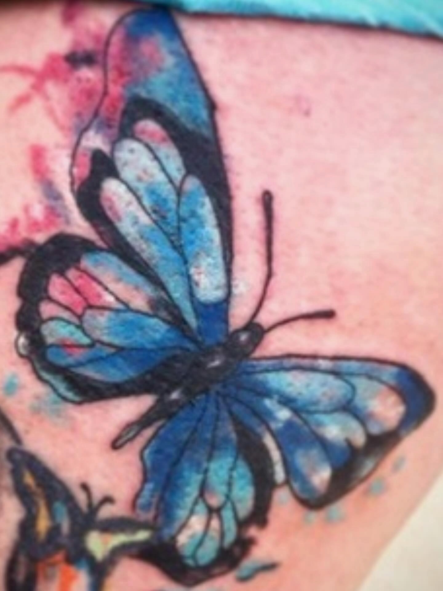 Blue butterfly watercolor tattoo on the thigh by @juiceinkythings