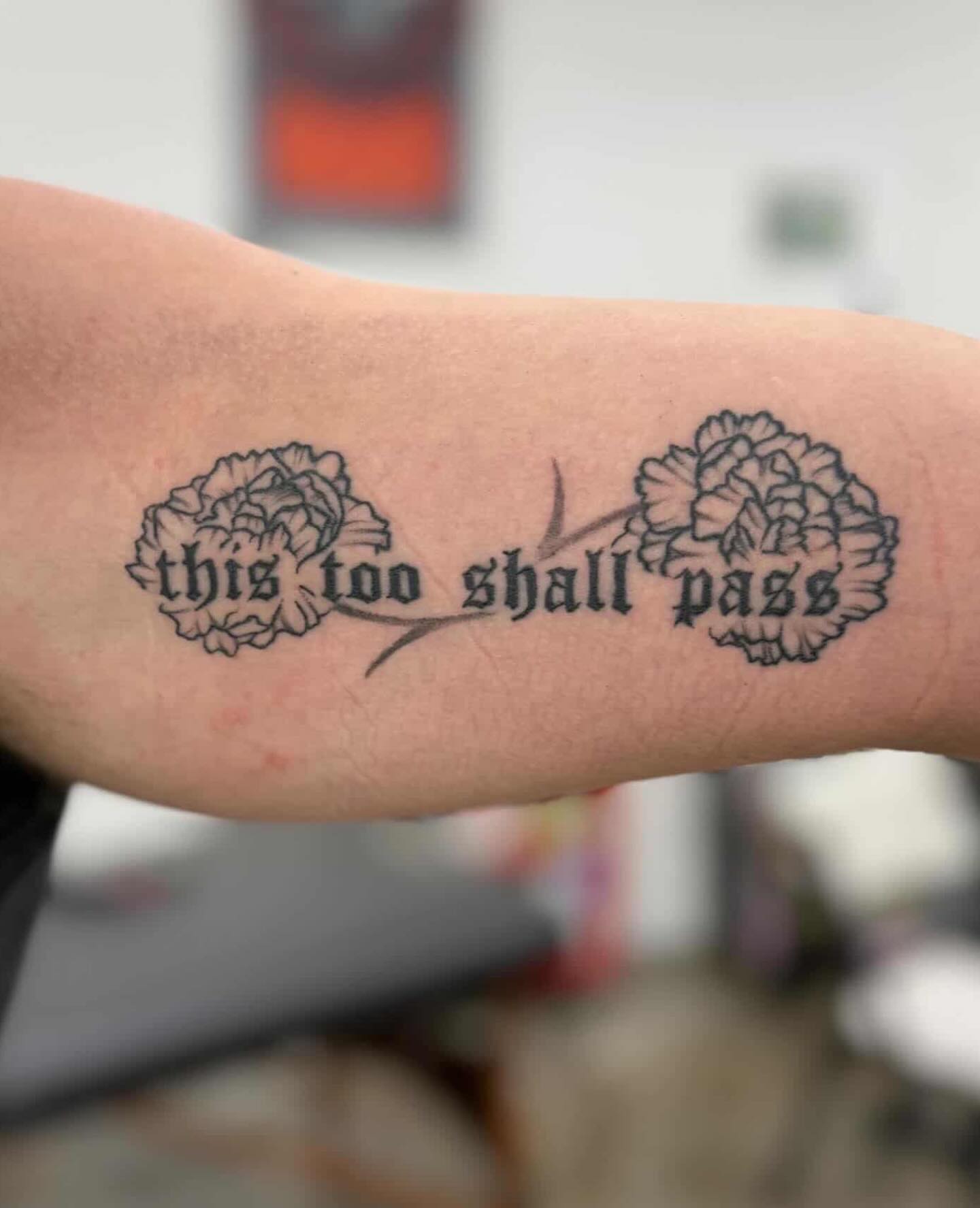Flowers and infinity black and grey tattoo on the forearm by Devin