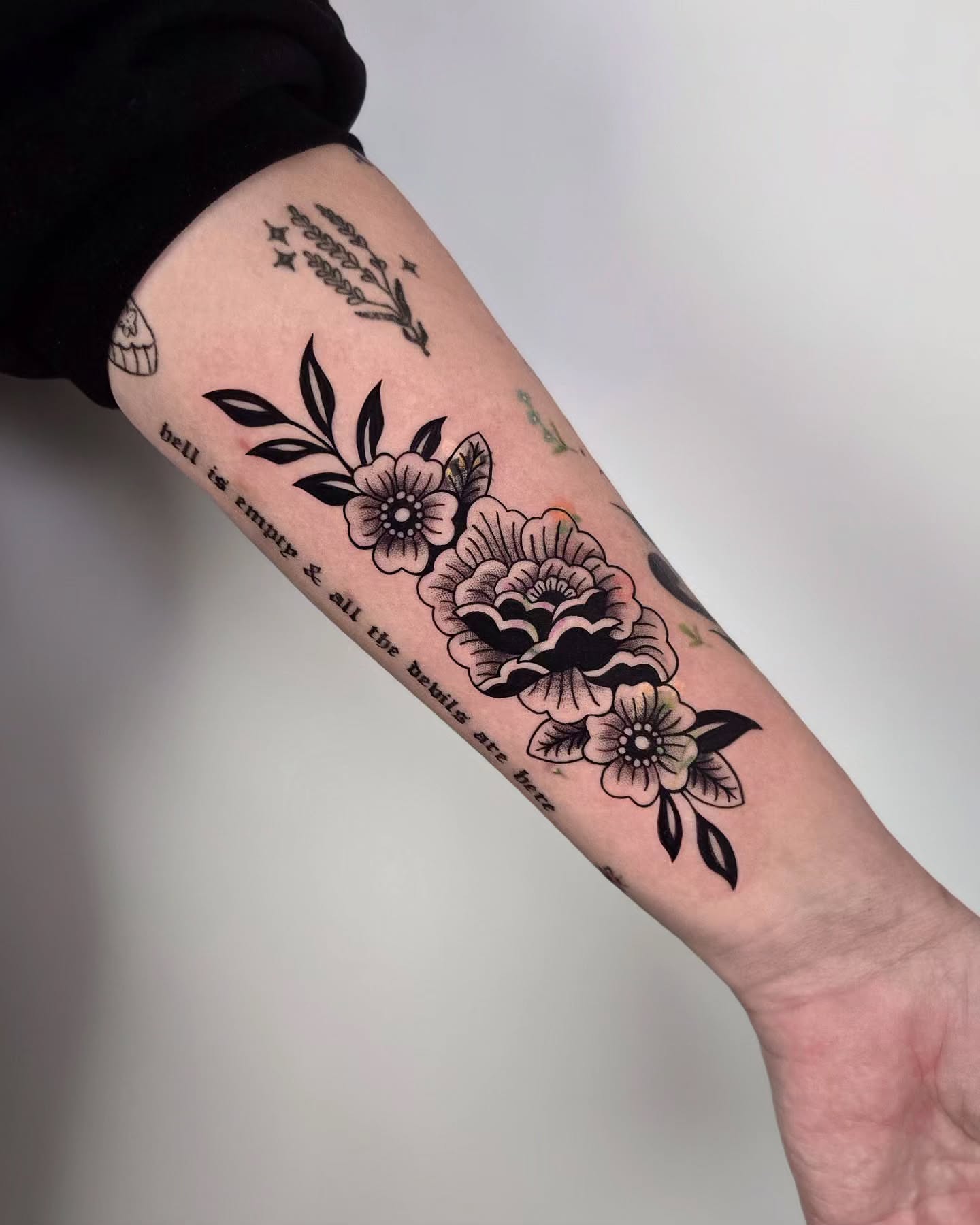 Flowers and text black and grey tattoo on the forearm by Kirstie Lew Tattoo