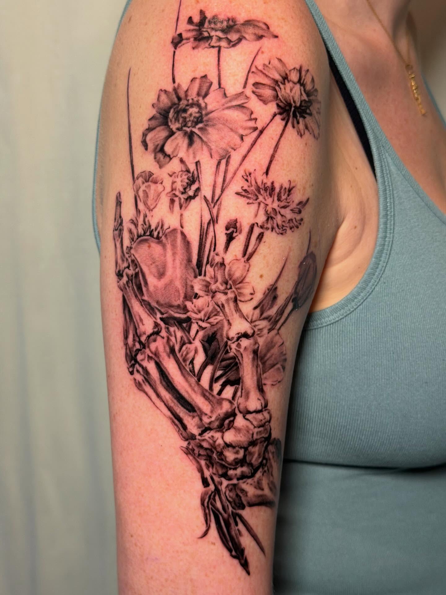 Flowers and bones realism tattoo on the upper arm by James Nelson