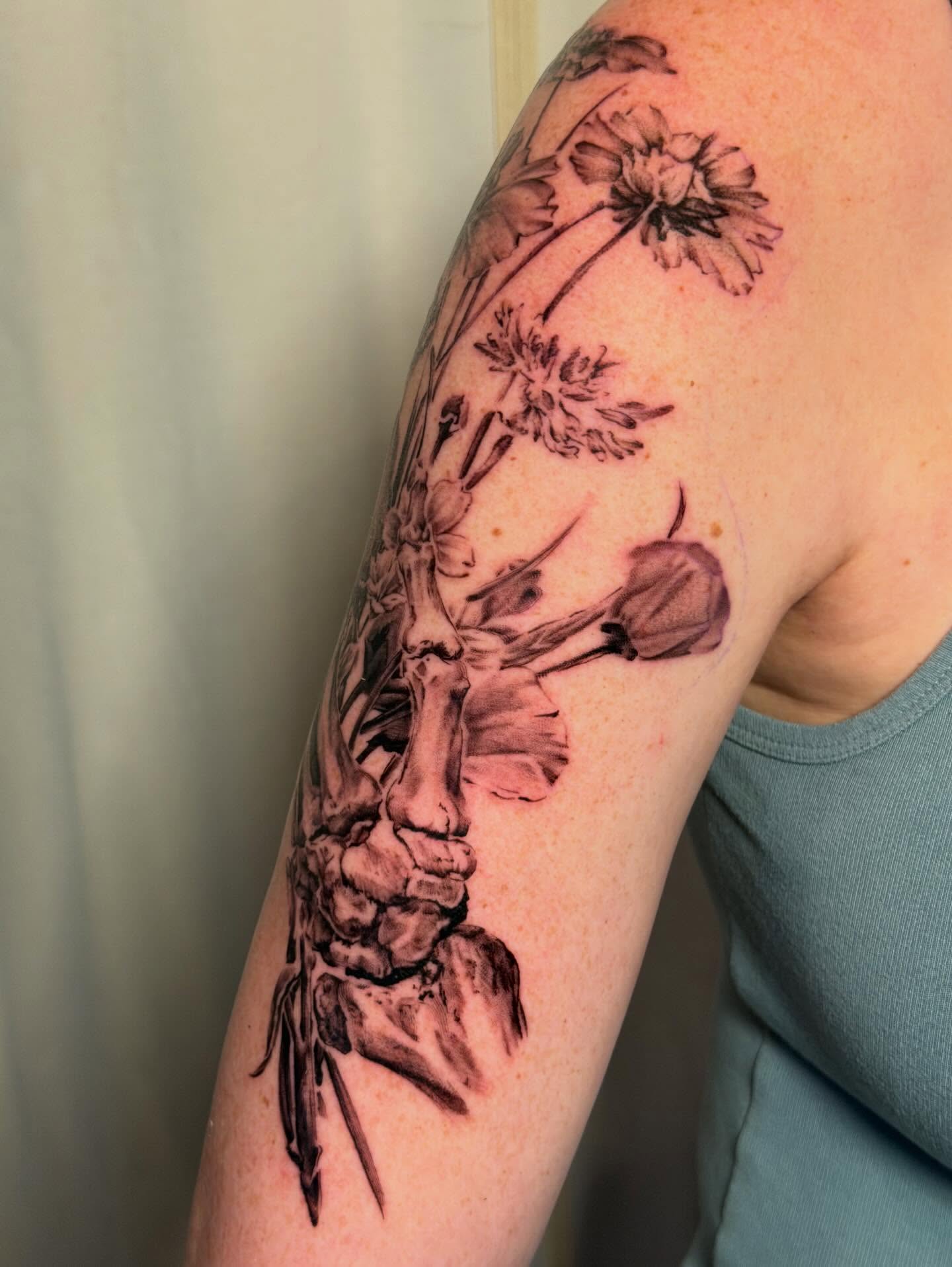 Flowers and skeleton realism tattoo on the upper arm by James Nelson