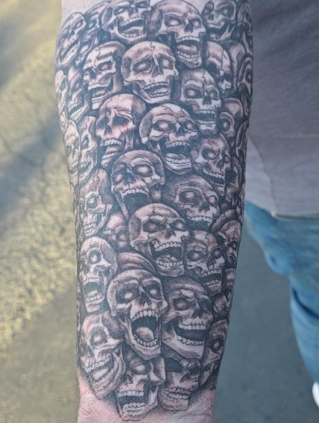 Pile of skulls realism tattoo on the forearm by Bosco Layne