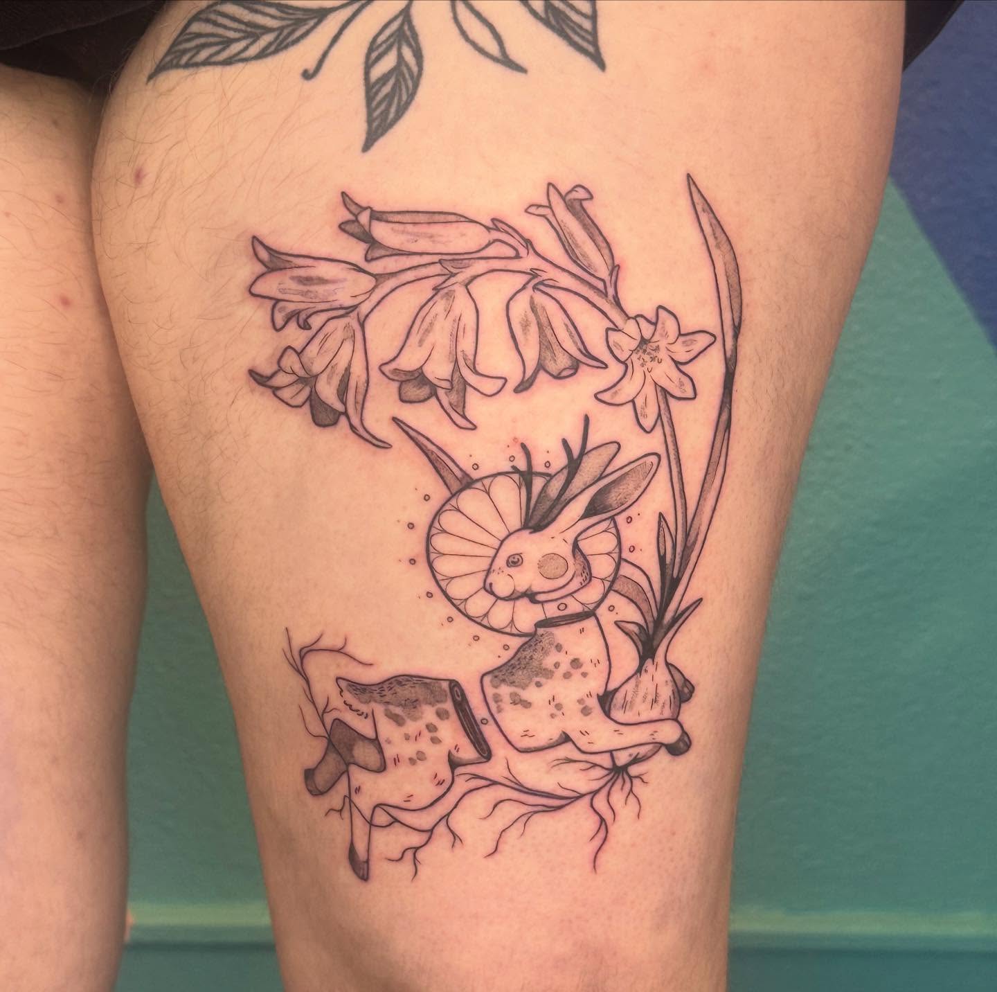 Rabbit and flowers black and grey tattoo on the thigh by Ivy