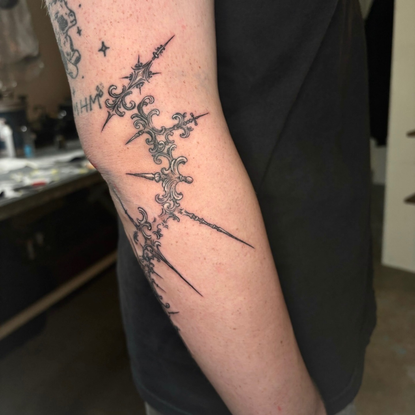 Crosses and flourishes geometric tattoo on the forearm by Quin Walker