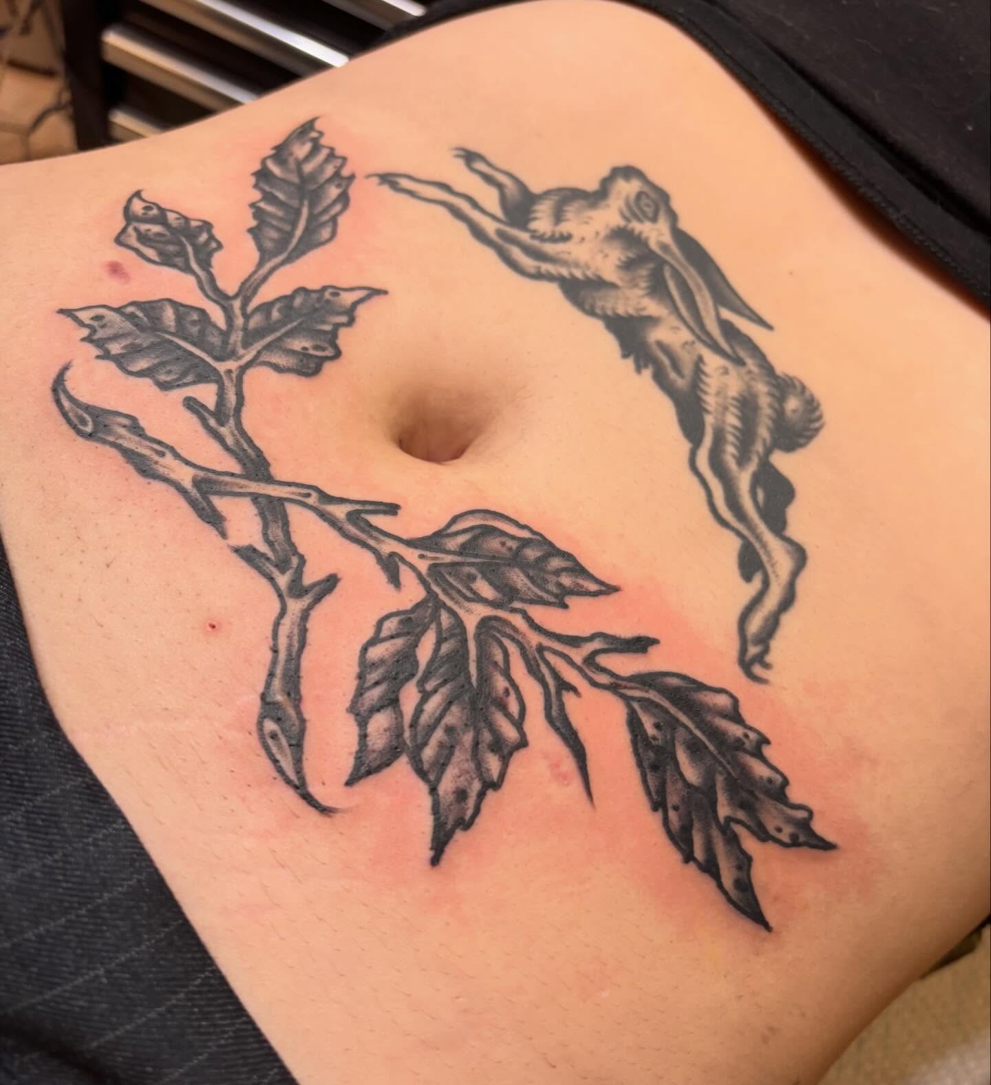 Hare and branch black and grey tattoo on the torso by Steve Reid