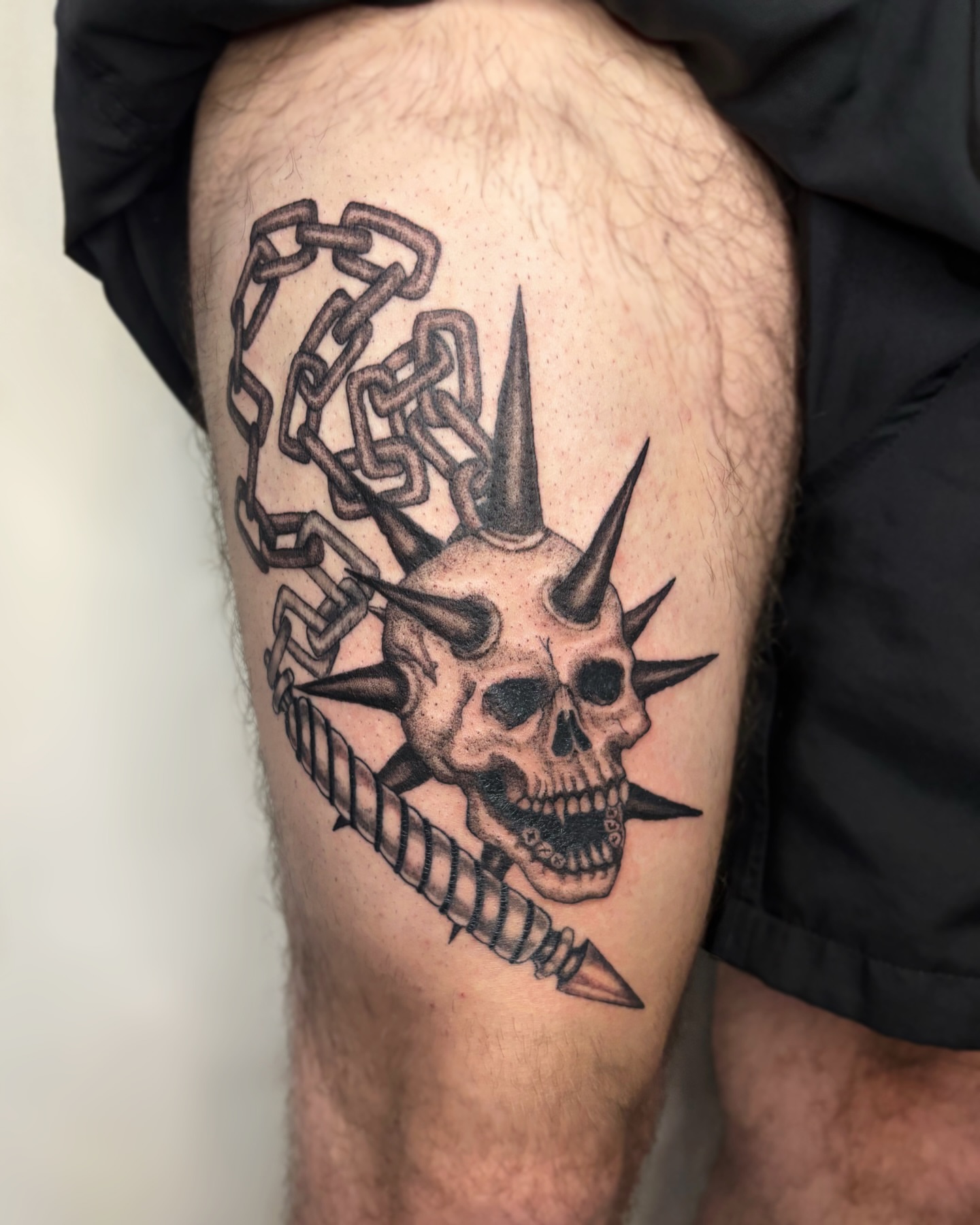 Skull with spikes realism tattoo on the thigh by Cooper, Portland, Oregon