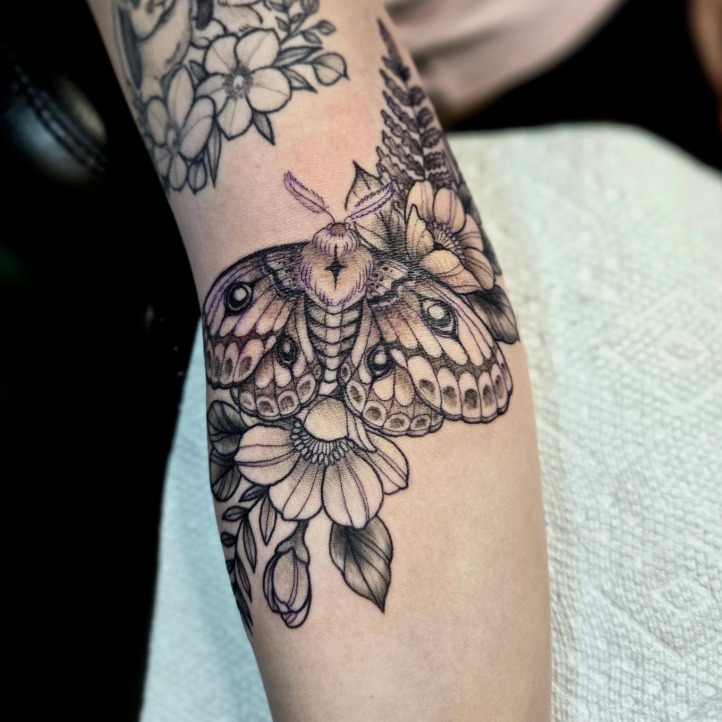 Moth and flowers realism tattoo on the forearm by Amanda Hinrichs