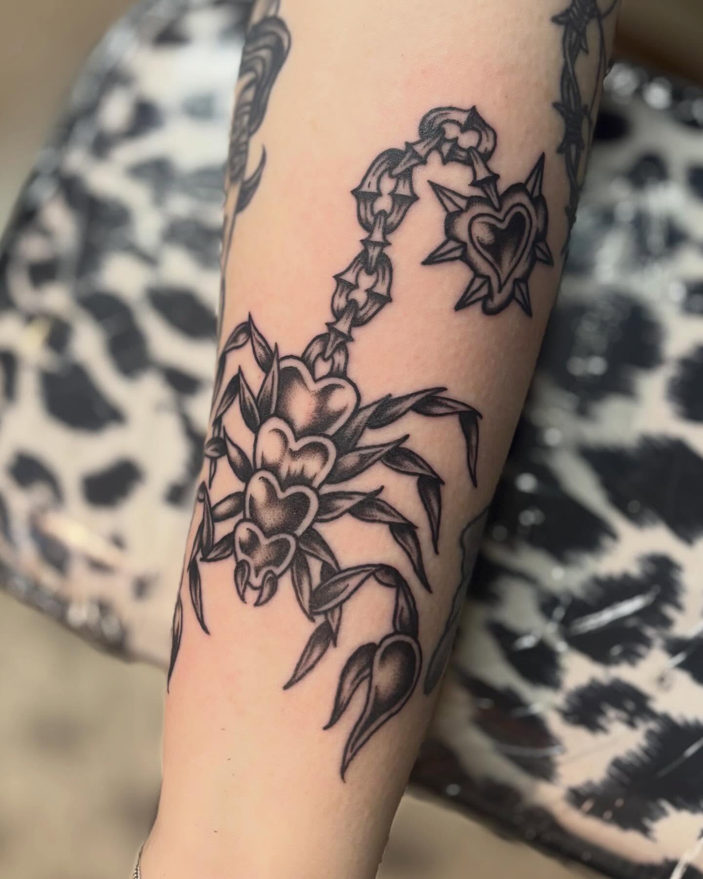 Flower and heart black and grey tattoo on the forearm by Tia Cave