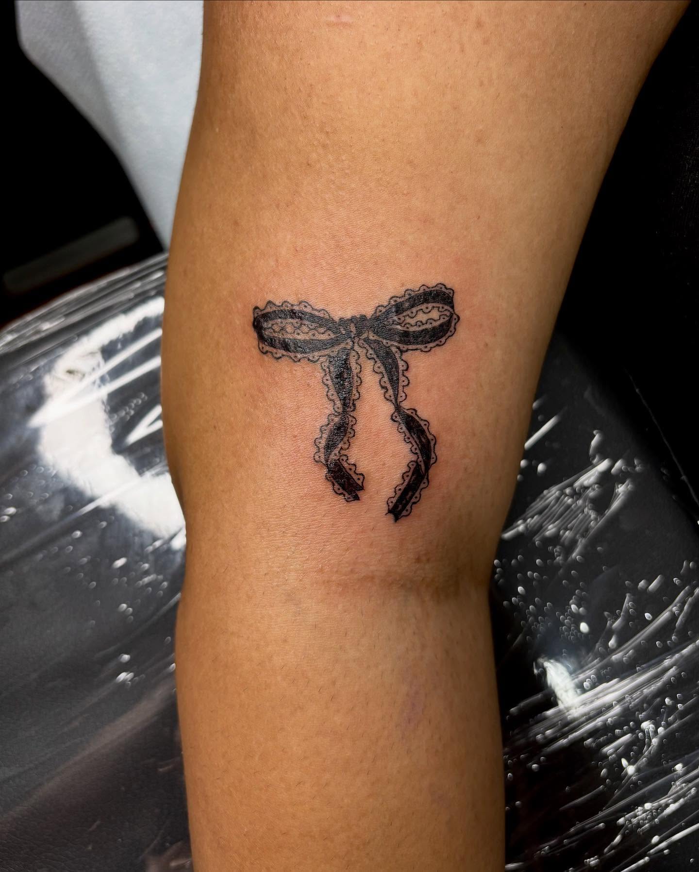 Lace bow black and grey tattoo on the forearm by kendle
