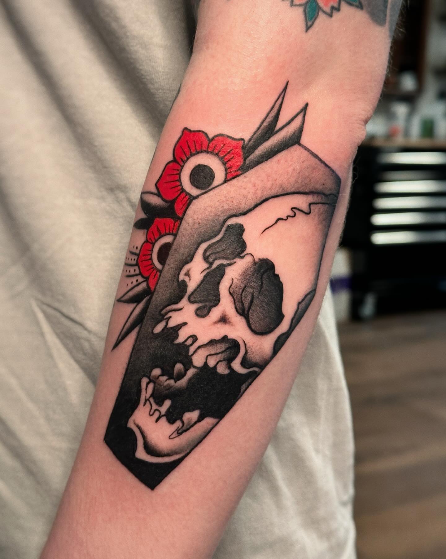 Skull and flower American traditional tattoo on the forearm by Craig Ryans