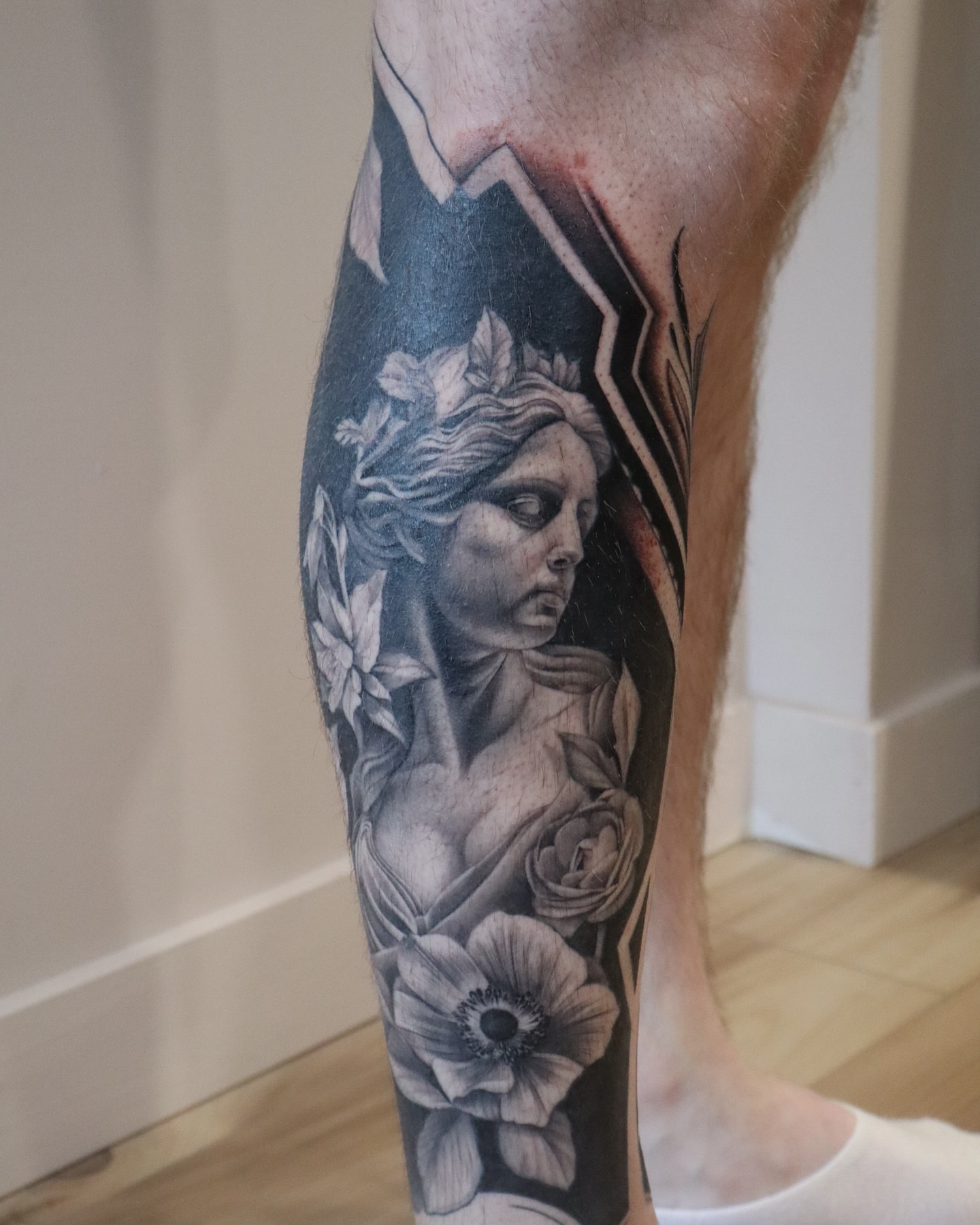 Statue with flowers realism tattoo on the calf by Anali De Laney