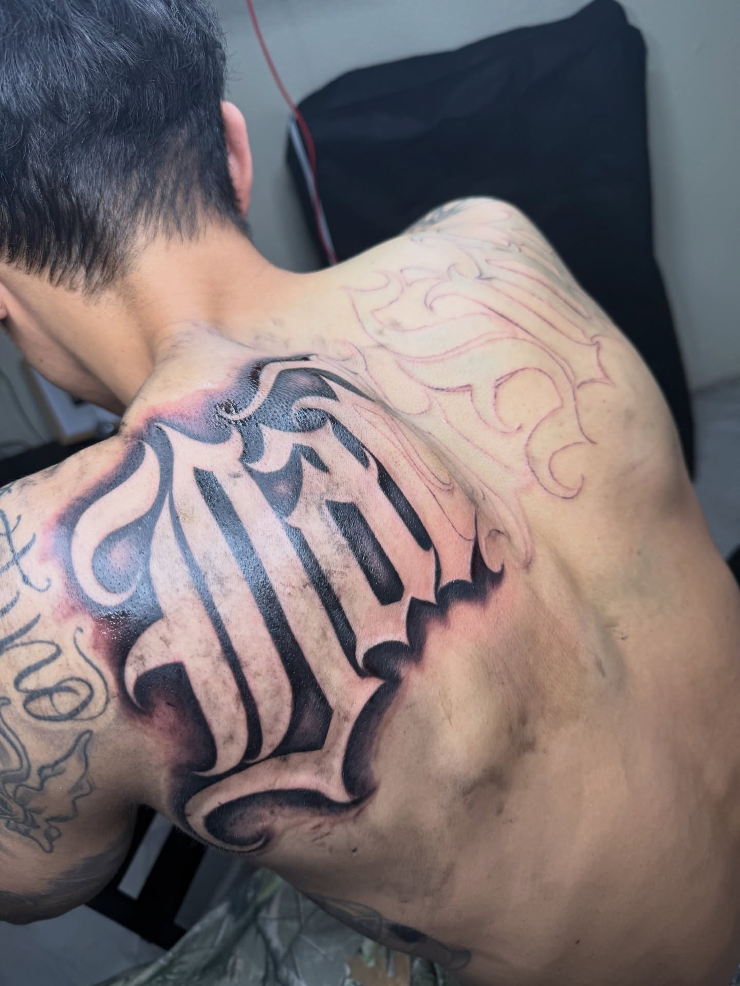 Lettering black and grey tattoo on the back by Daniel Lopez Tattoos