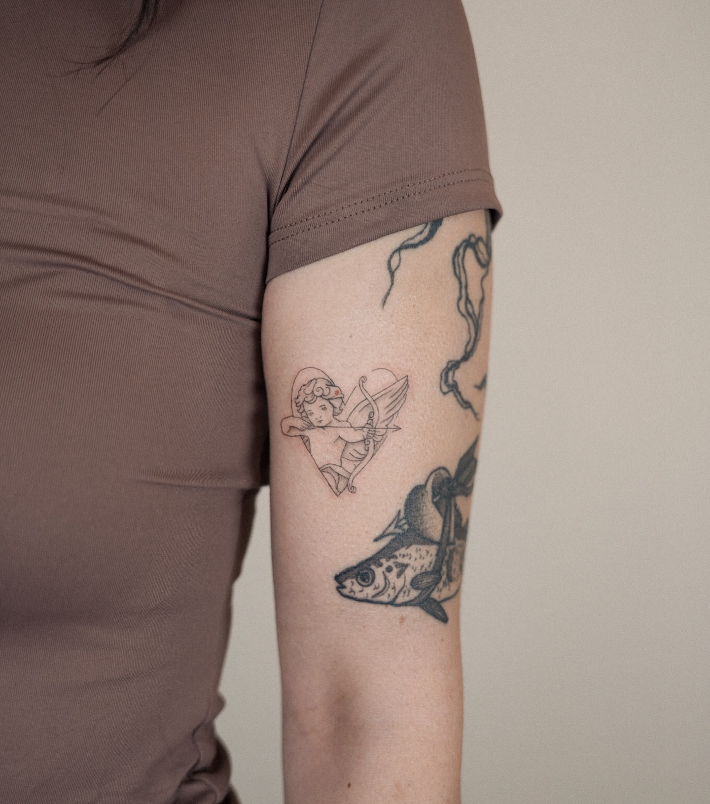 Angel with bow black and grey tattoo on the forearm by Helly March