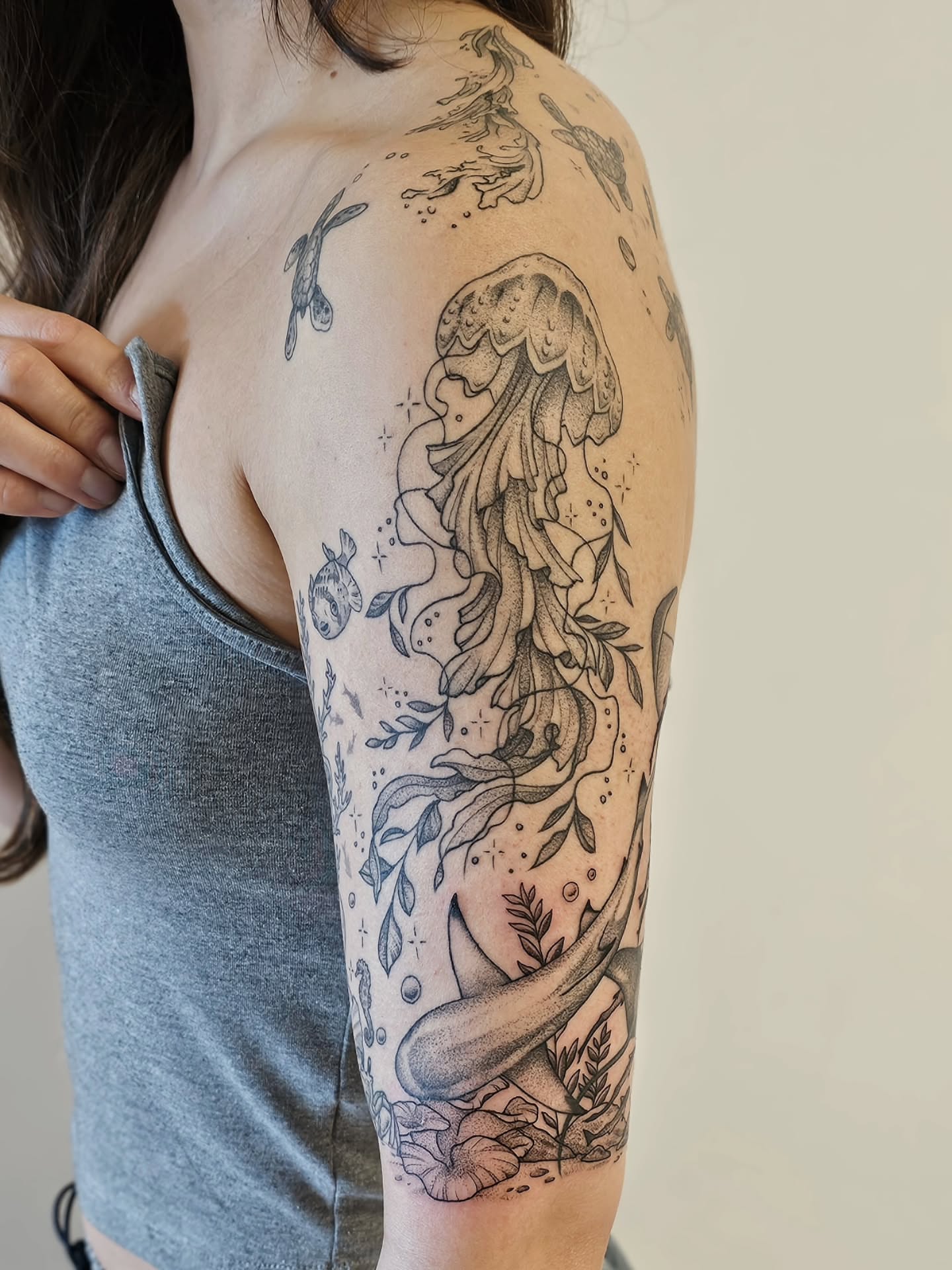 Jellyfish and seaweed dotwork tattoo on the upper arm by Kylie Lund