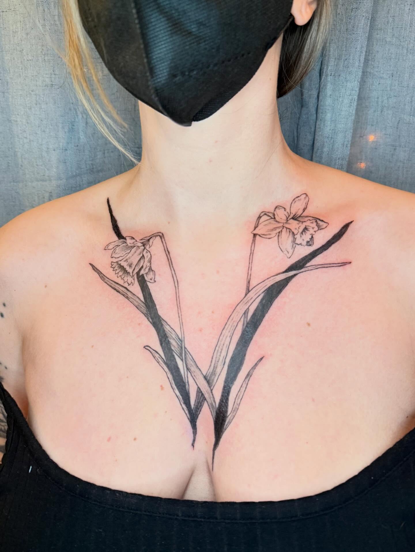 Daffodil black and grey tattoo on the chest by Emily Rose Lumsdaine