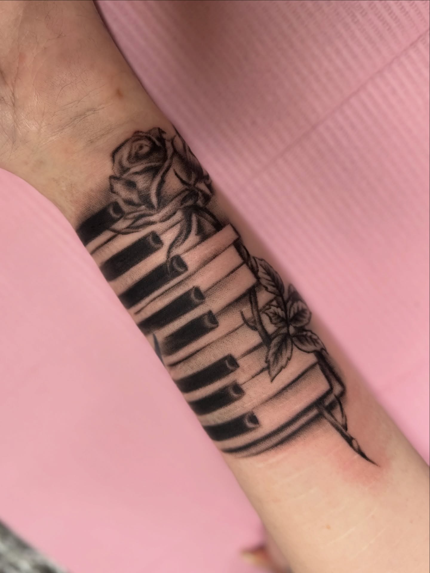 Piano keys and rose black and grey tattoo on the forearm by Chloe Marie