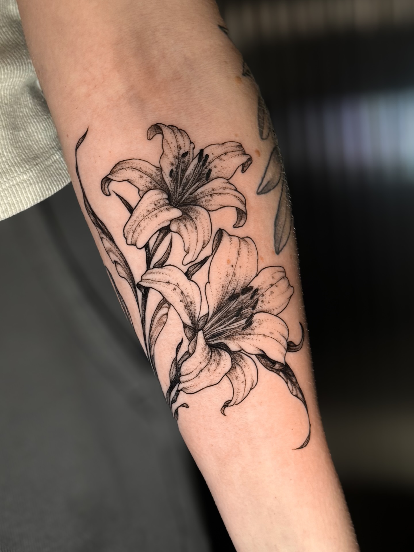 Lilies dotwork tattoo on the forearm by Kam Mills