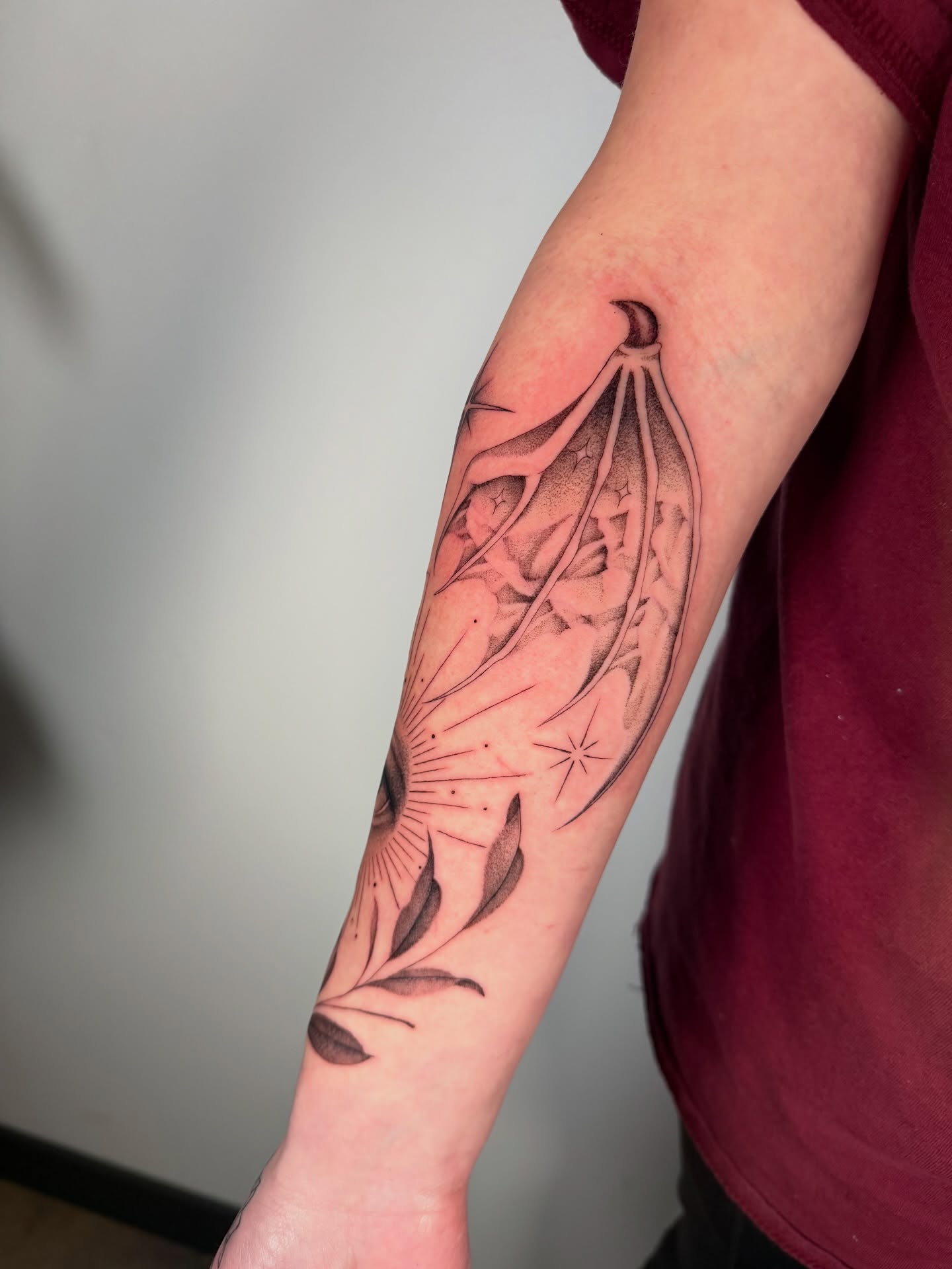 Wing and starburst dotwork tattoo on the forearm by Cyn
