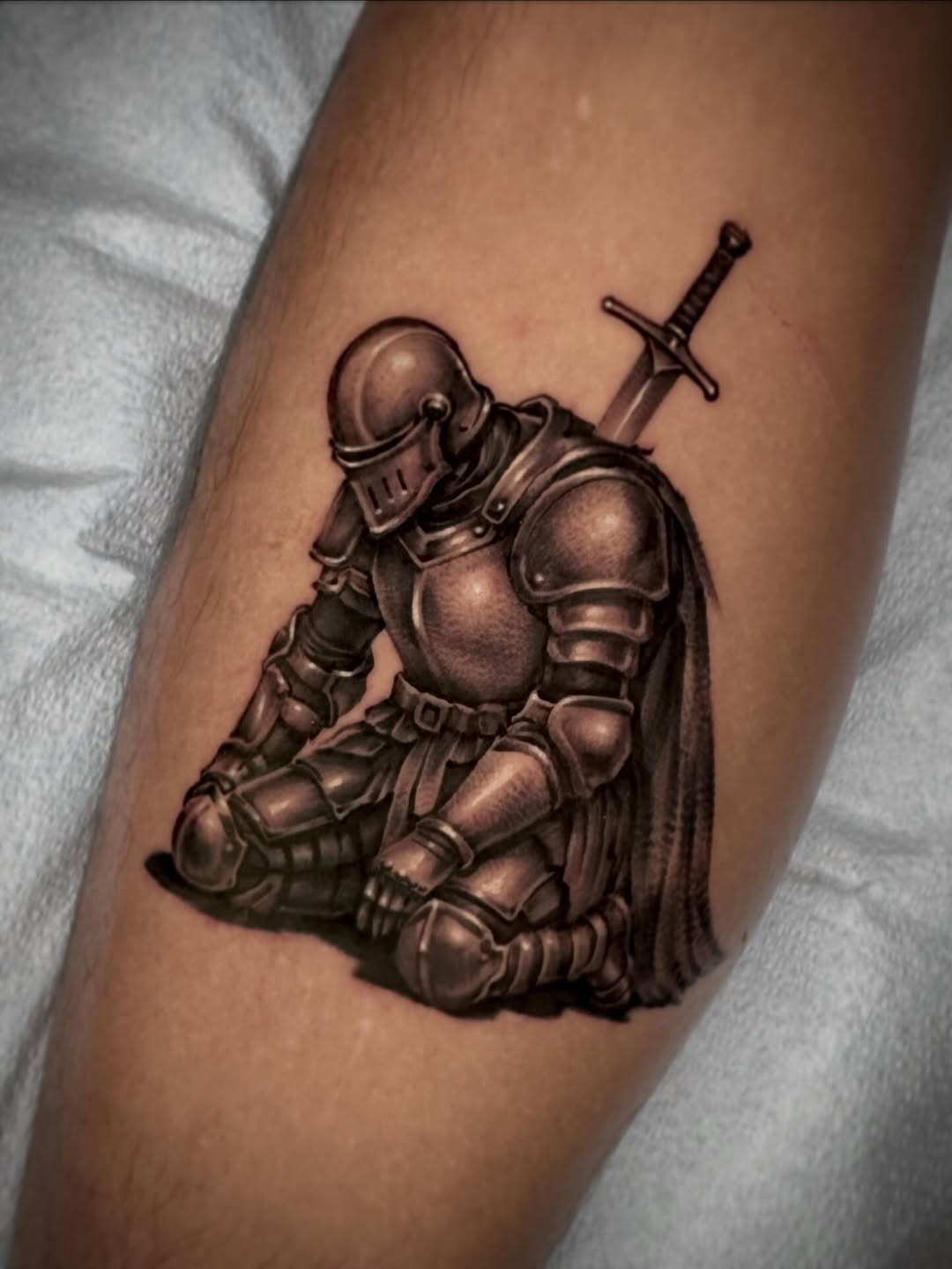 Kneeling knight with sword realism tattoo on the forearm by David Torres