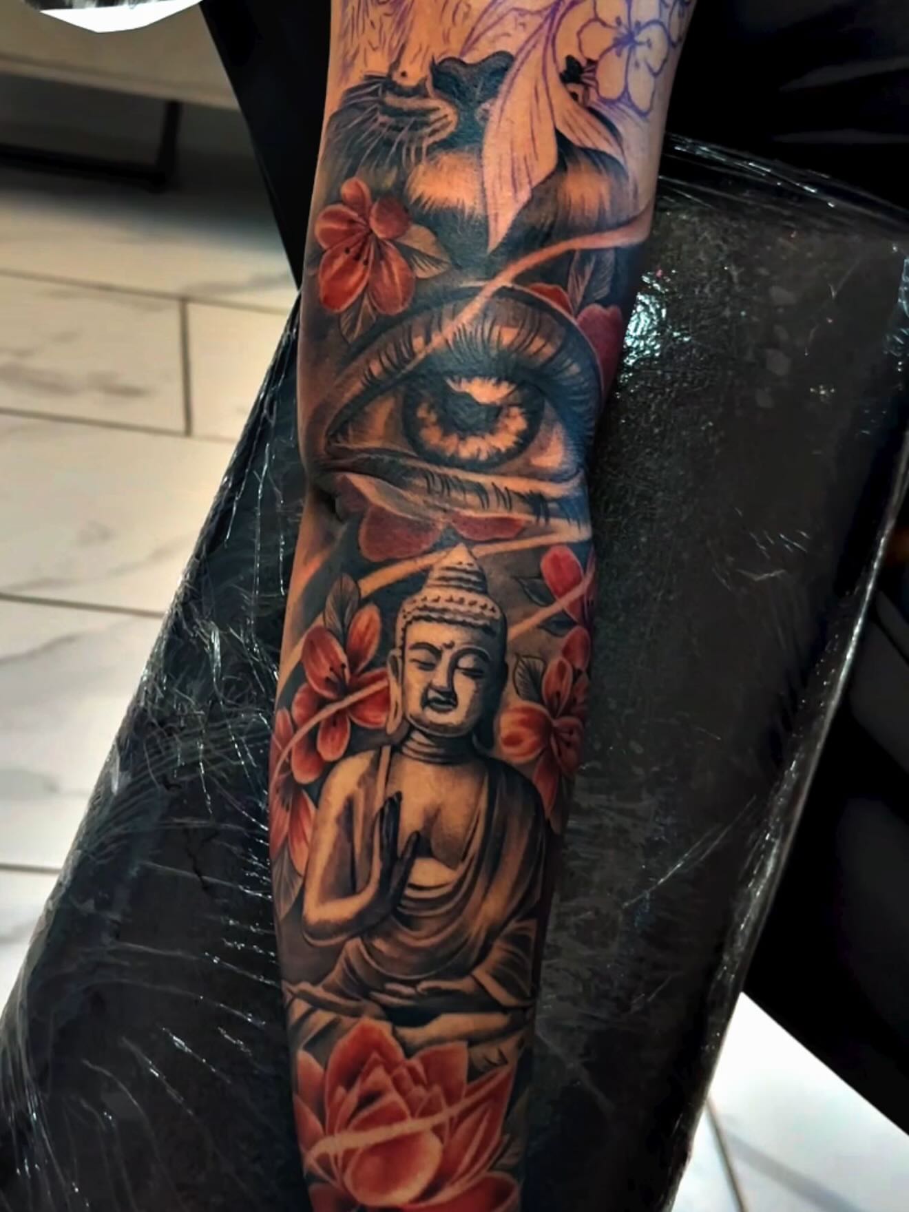 Buddha statue with flowers realism tattoo on the forearm by Adrian gonzalez...