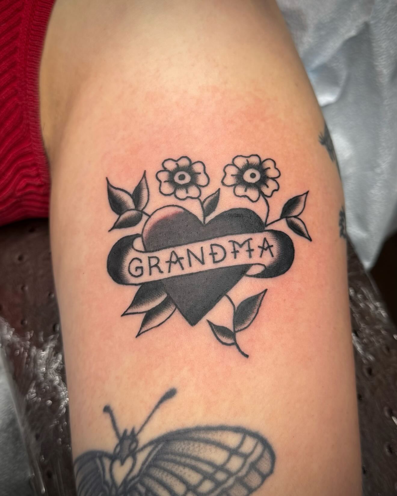 Heart with flowers and ribbon American traditional tattoo on the forearm by kalli berry