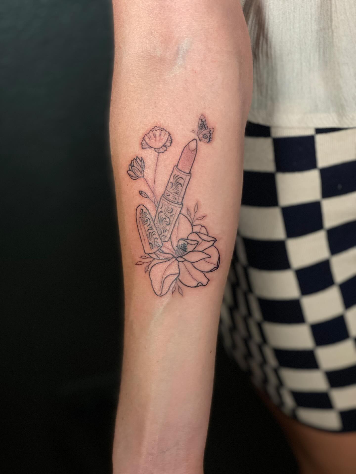 Lipstick and flowers black and grey tattoo on the forearm by Annie Mess