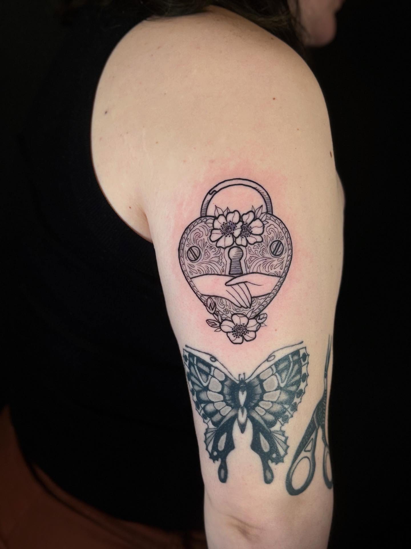 Heart lock and butterfly geometric tattoo on the forearm by Annie Mess
