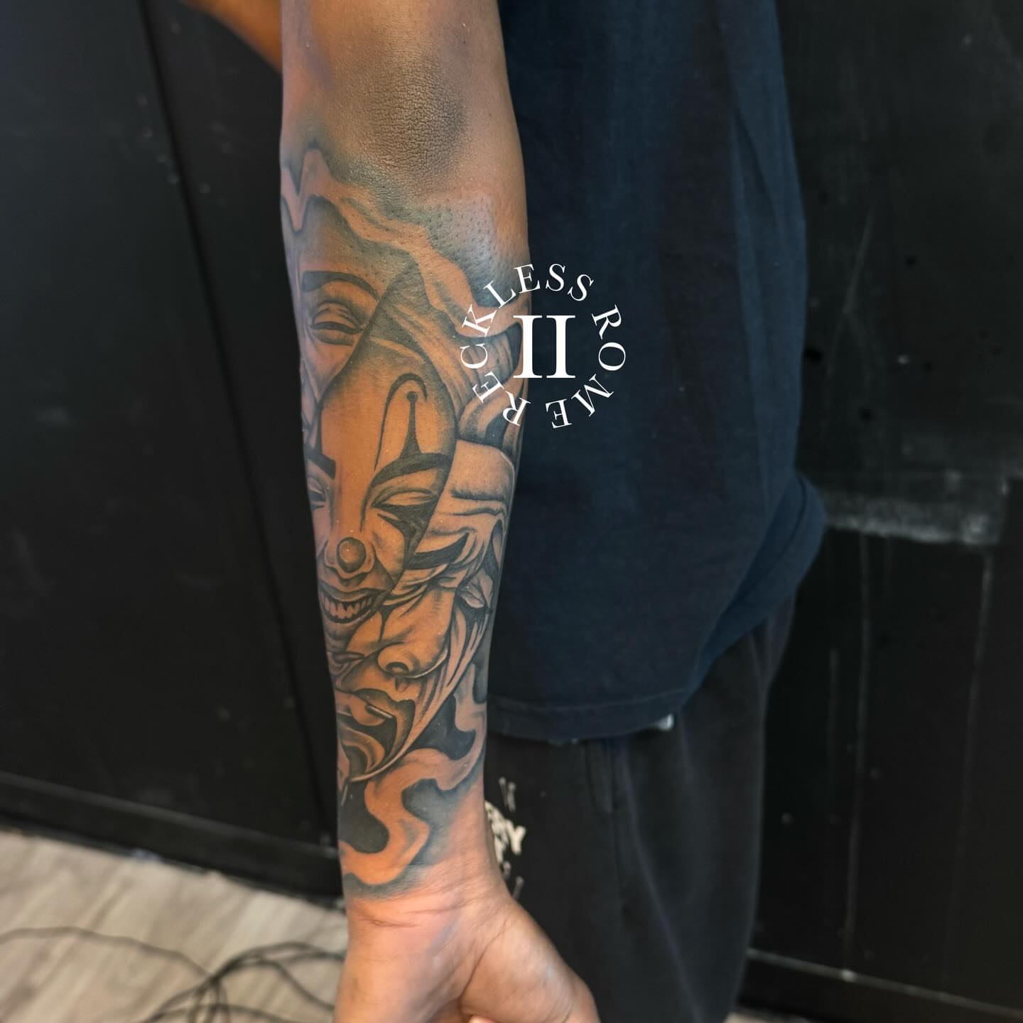 Mask black and grey tattoo on the forearm by Rome