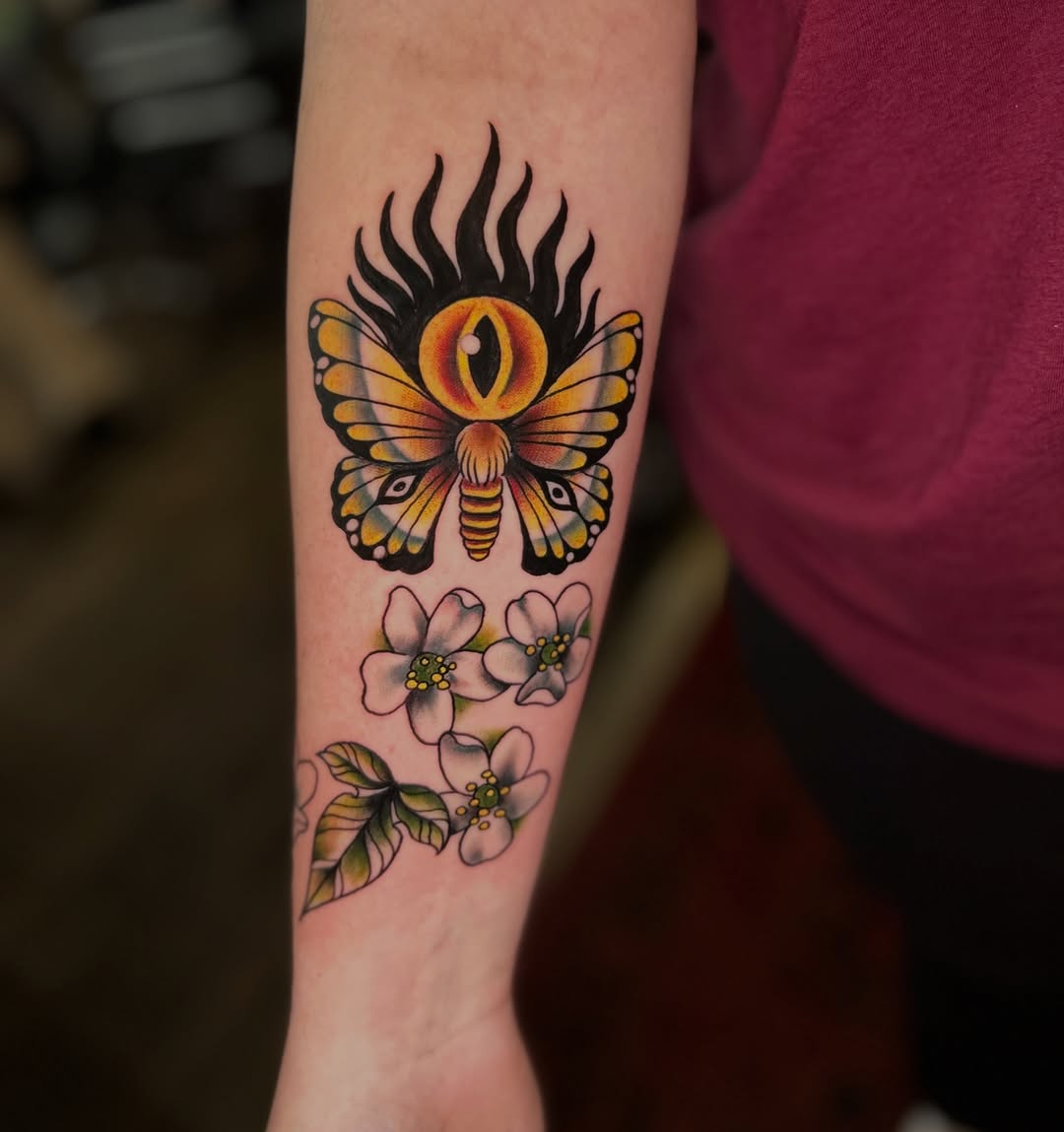 Moth with eye and flowers American traditional tattoo on the forearm by Olivia Marie