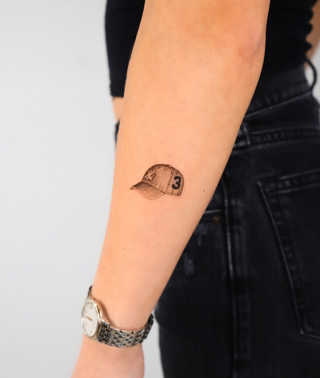 Baseball cap minimalist tattoo on the forearm by Fine Line, New York, New York