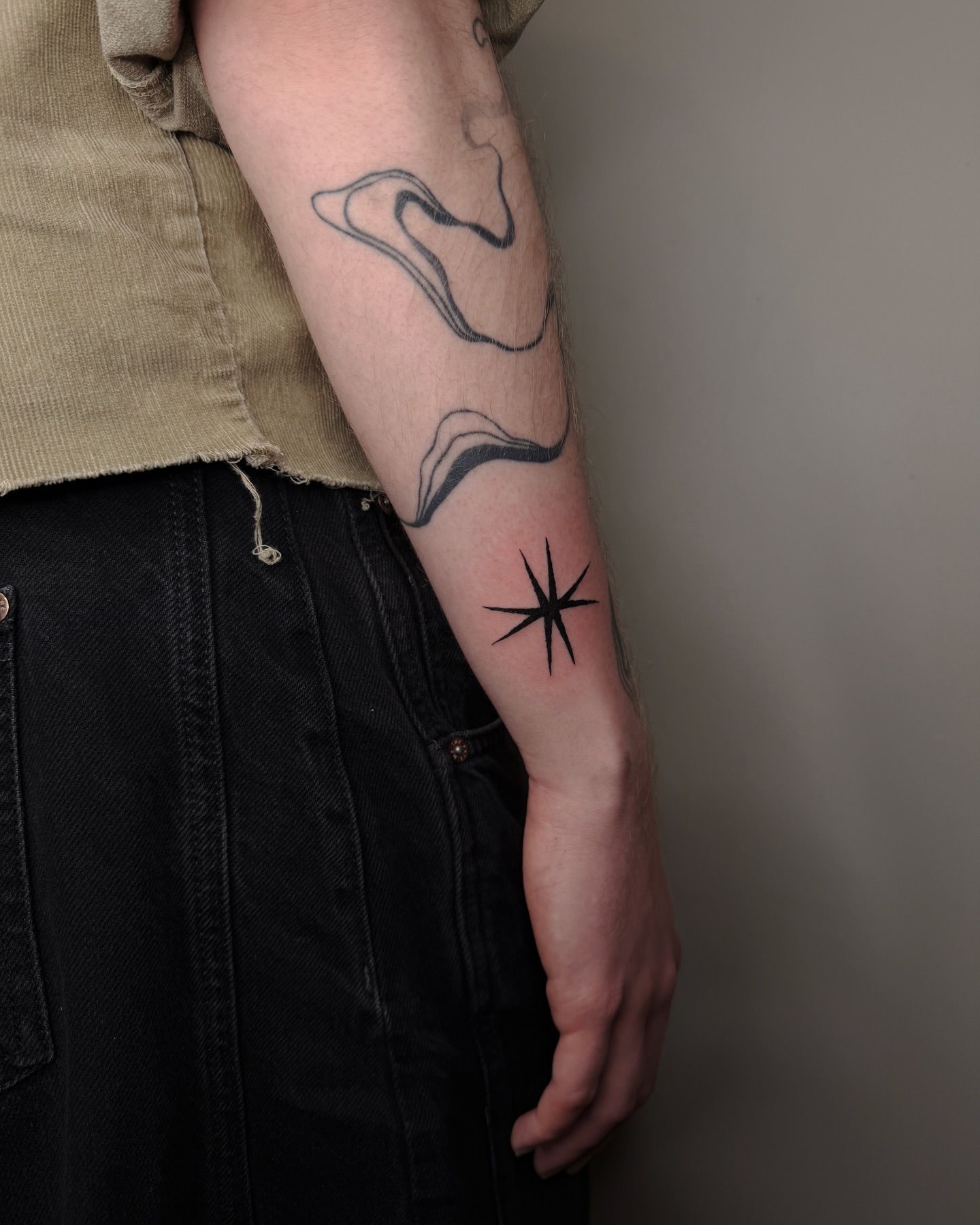 Wave and starburst black and grey tattoo on the forearm by Haza