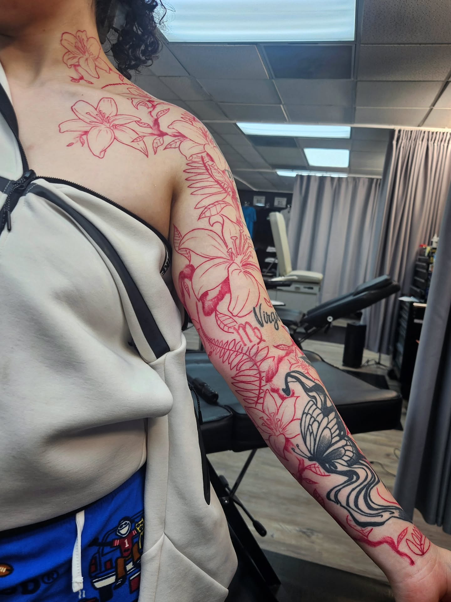 Floral design with butterfly new school tattoo on the upper arm by Damian Eames
