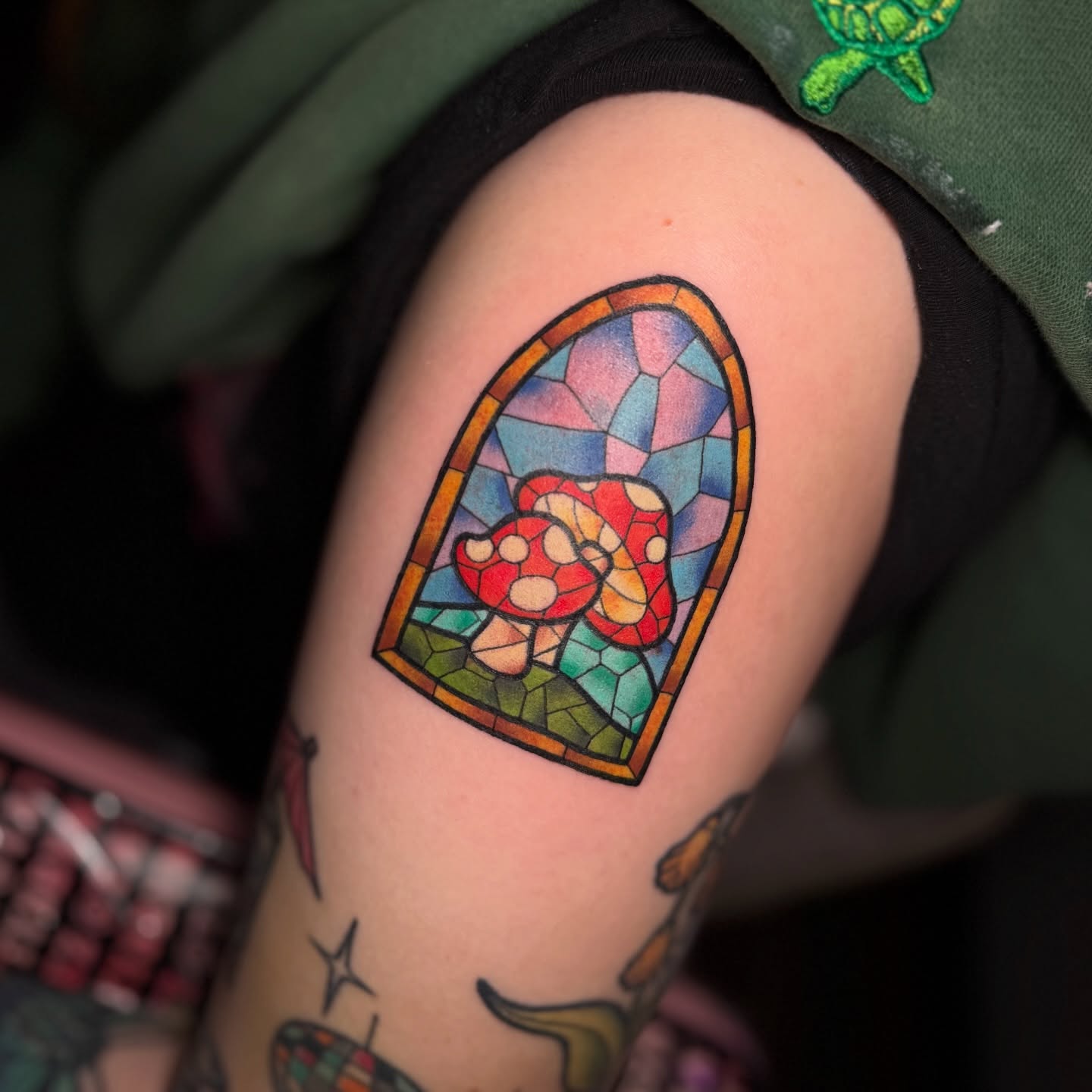 Stained glass window tattoo on the upper arm by Lyndze Masters