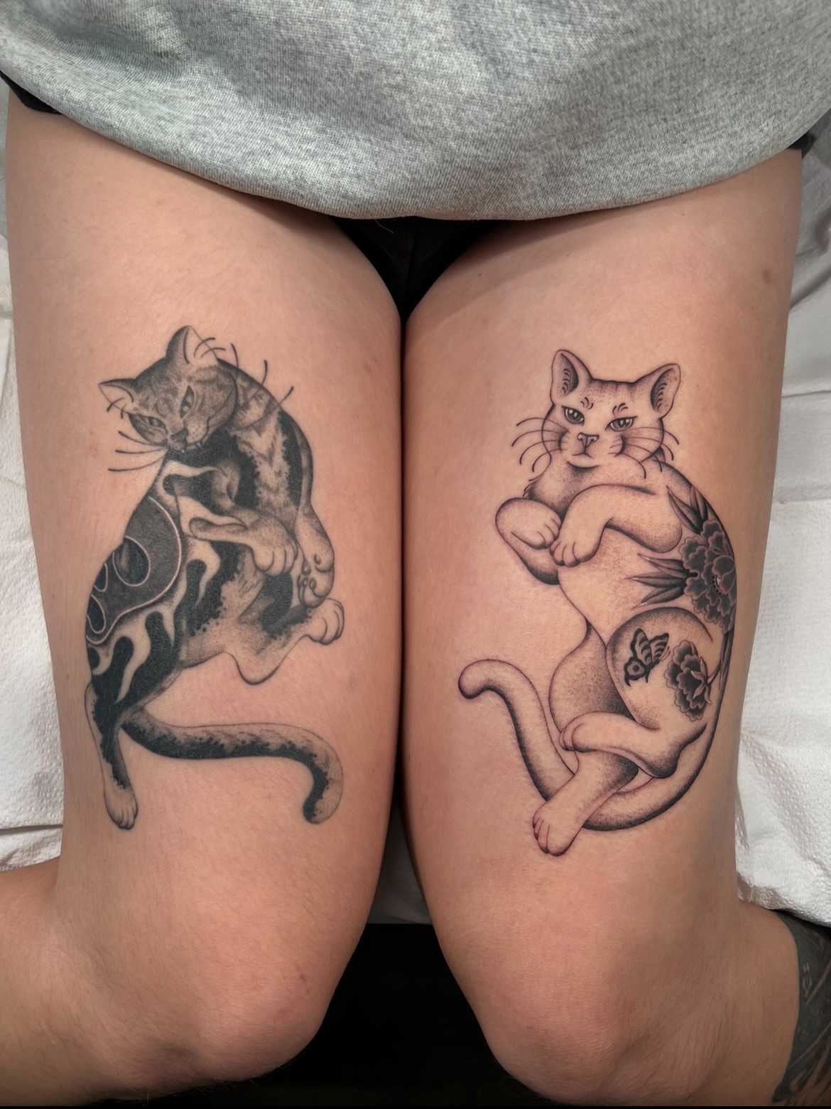 Cats black and grey tattoo on the thigh by Cassidy Maples