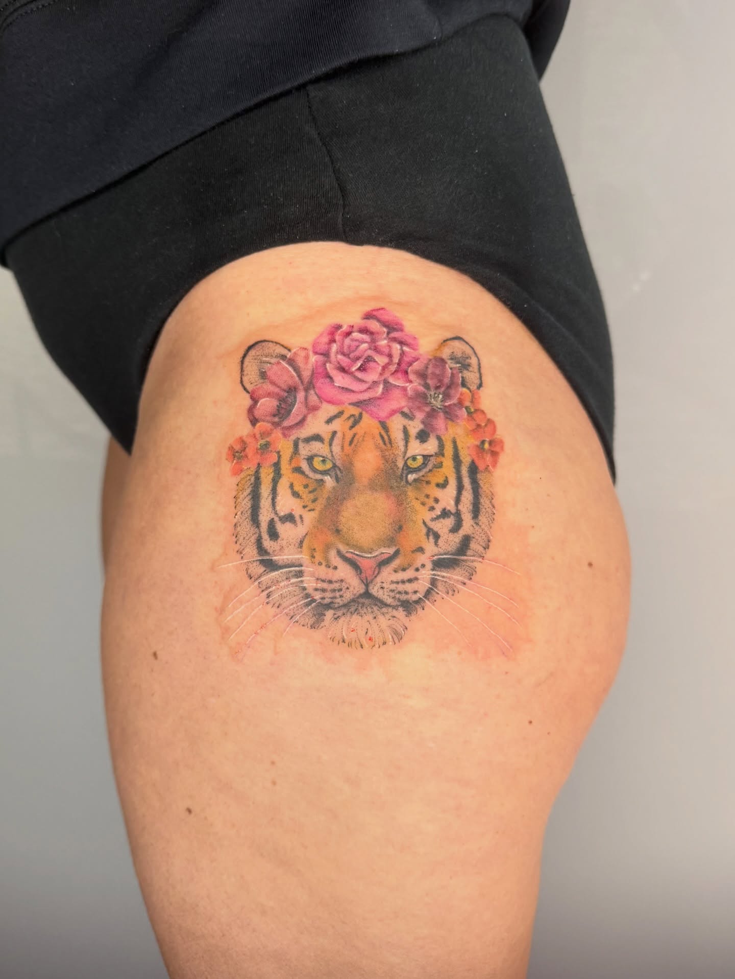 Tiger with flowers realism tattoo on the thigh by Brandie
