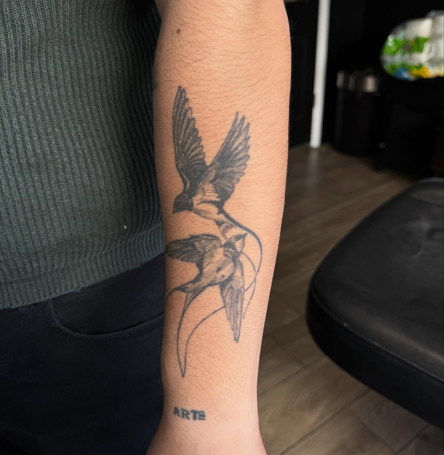 Swallows black and grey tattoo on the forearm by Mickey