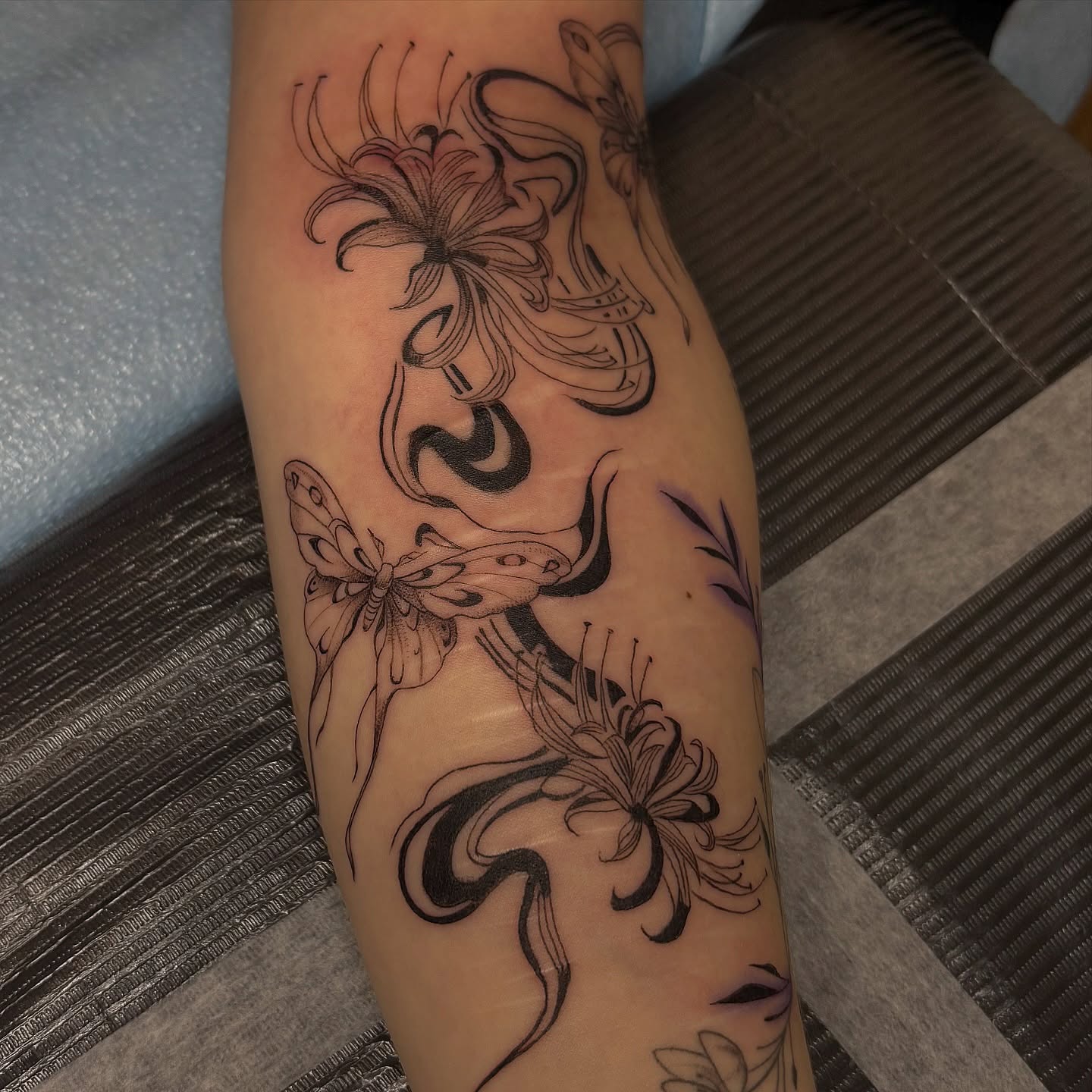 Floral and butterfly black and grey tattoo on the forearm by Sydney Gallucci