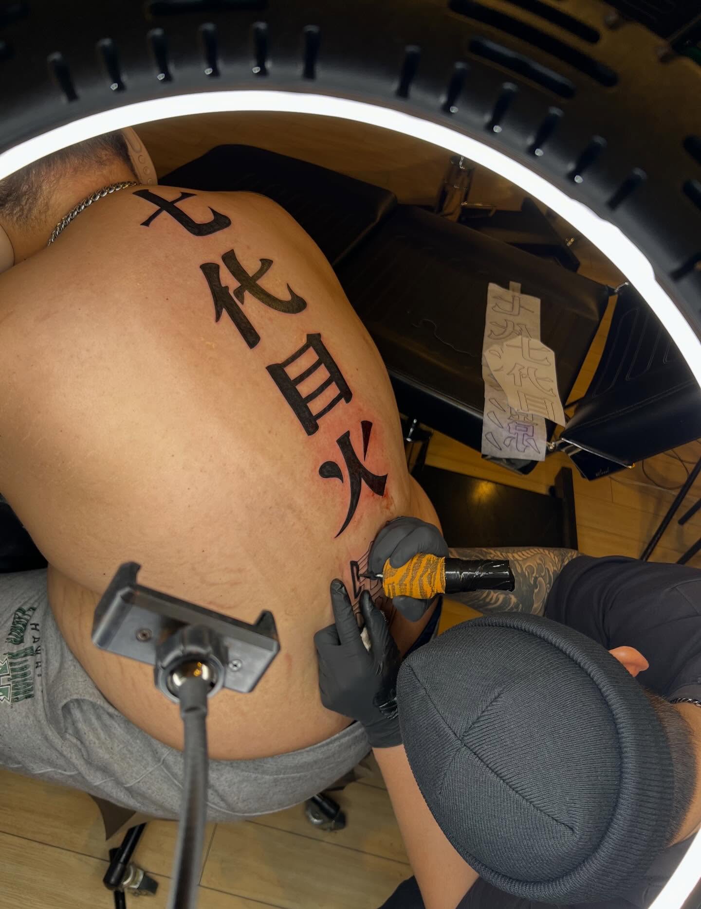Kanji characters black and grey tattoo on the back by Winston Thai