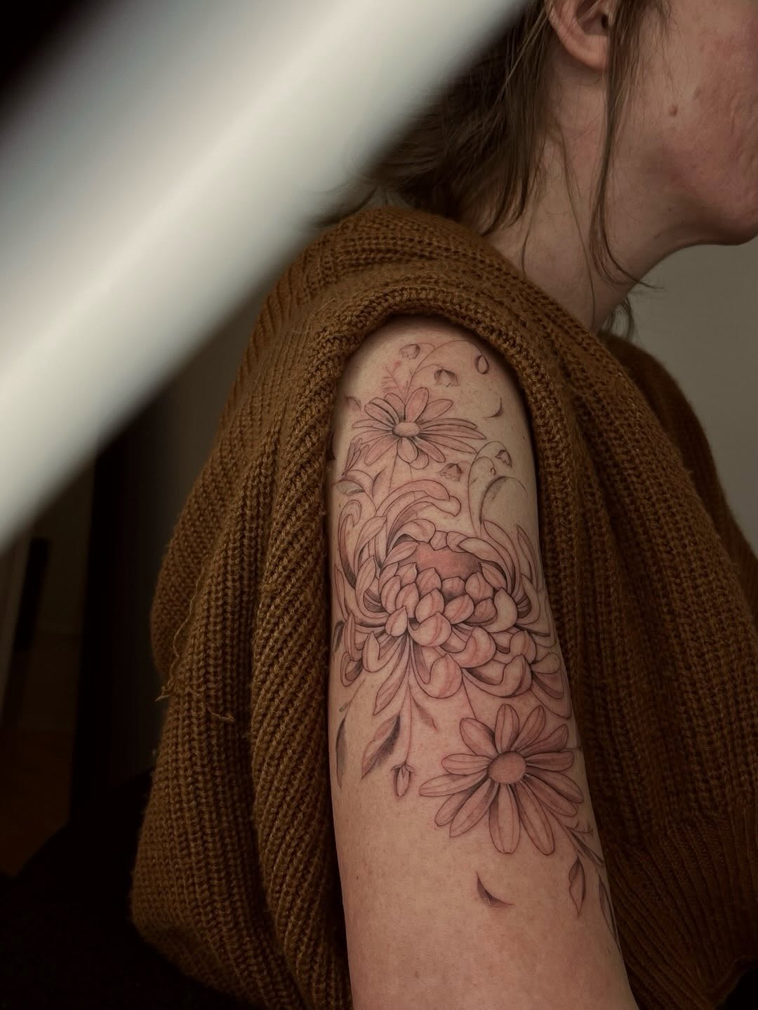 Chrysanthemum and daisies fine line tattoo on the upper arm by Mari