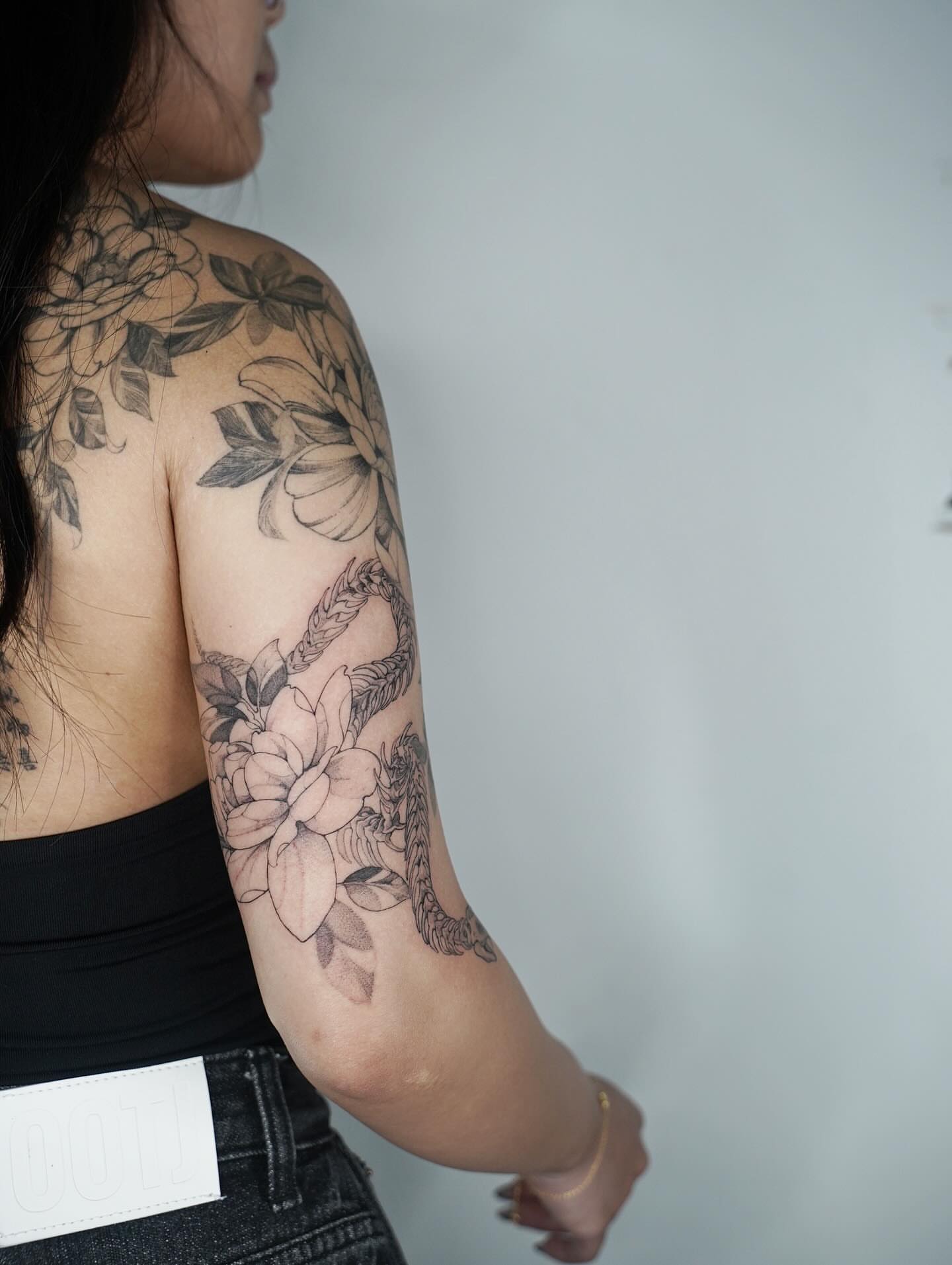 Lotus and dragon black and grey tattoo on the upper arm by Emma