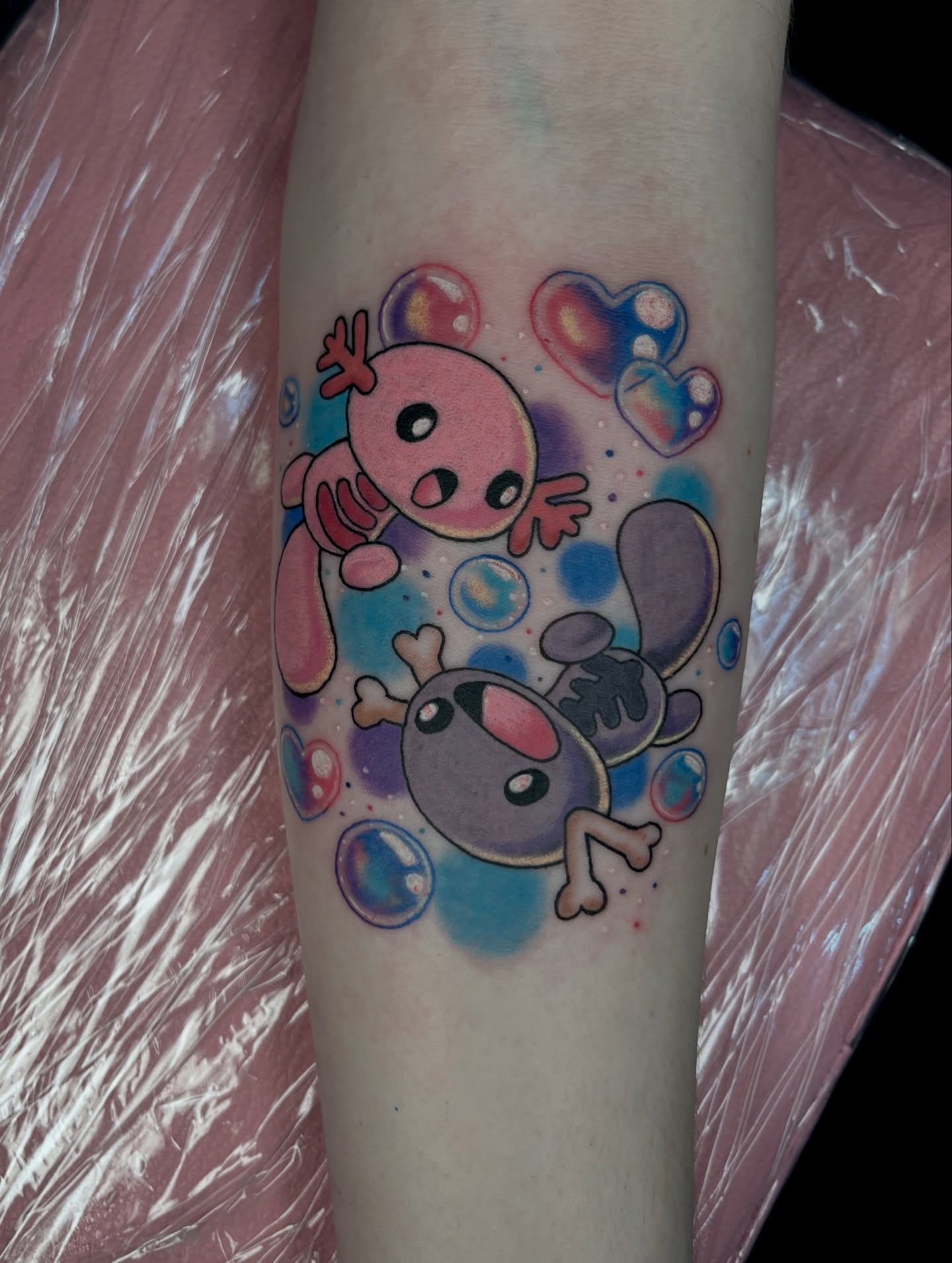 Kawaii axolotls watercolor tattoo on the forearm by Cheyanne Peck