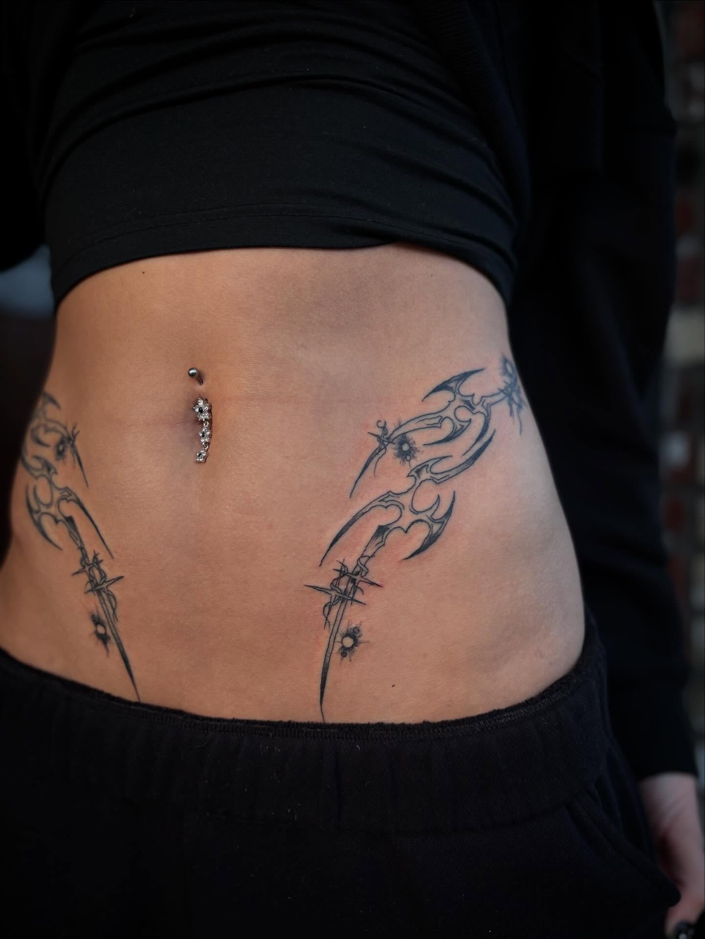 Swords tribal tattoo on the torso by Lauren Deets