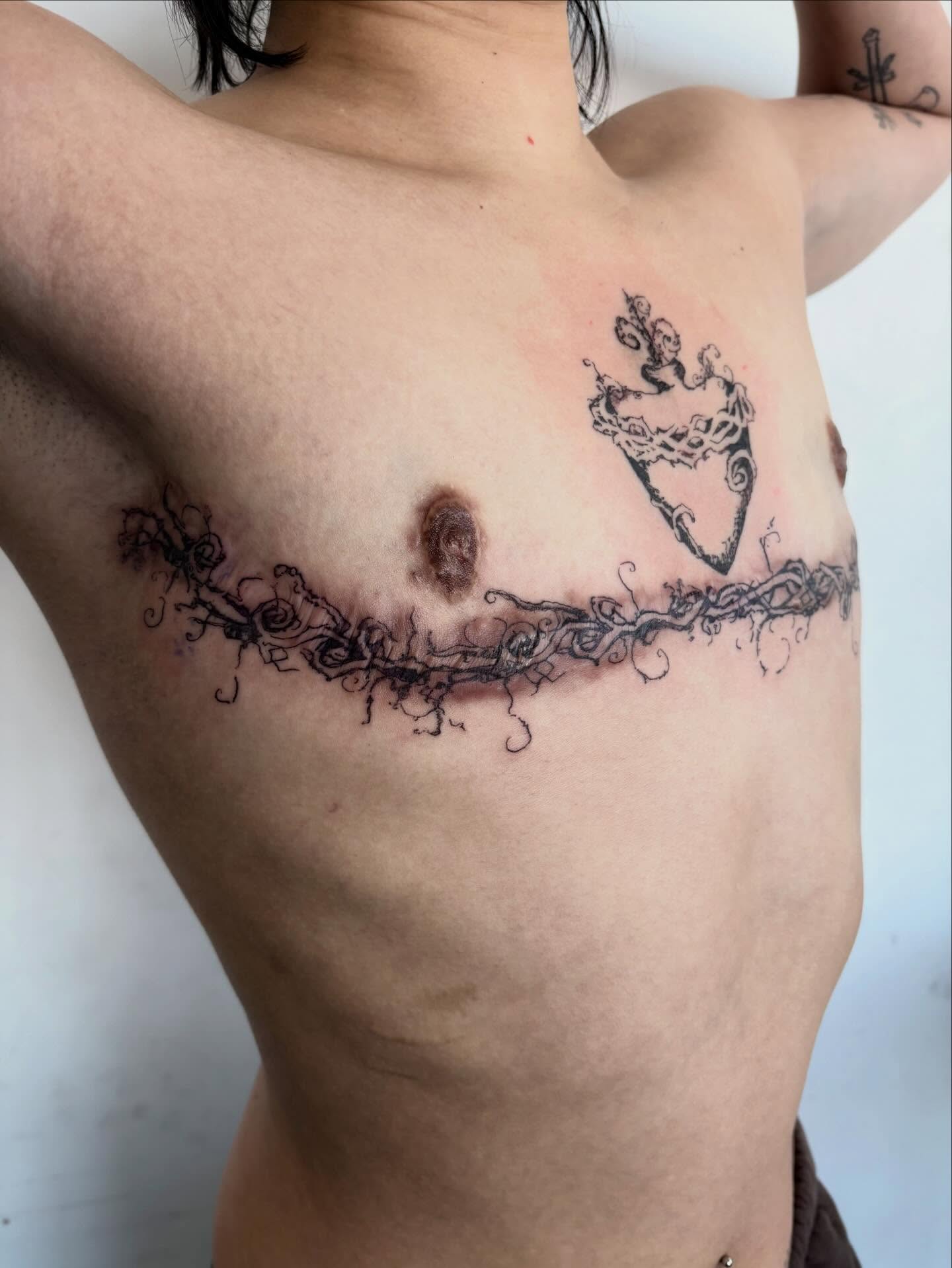 Vines and heart ornamental tattoo on the chest by madeline