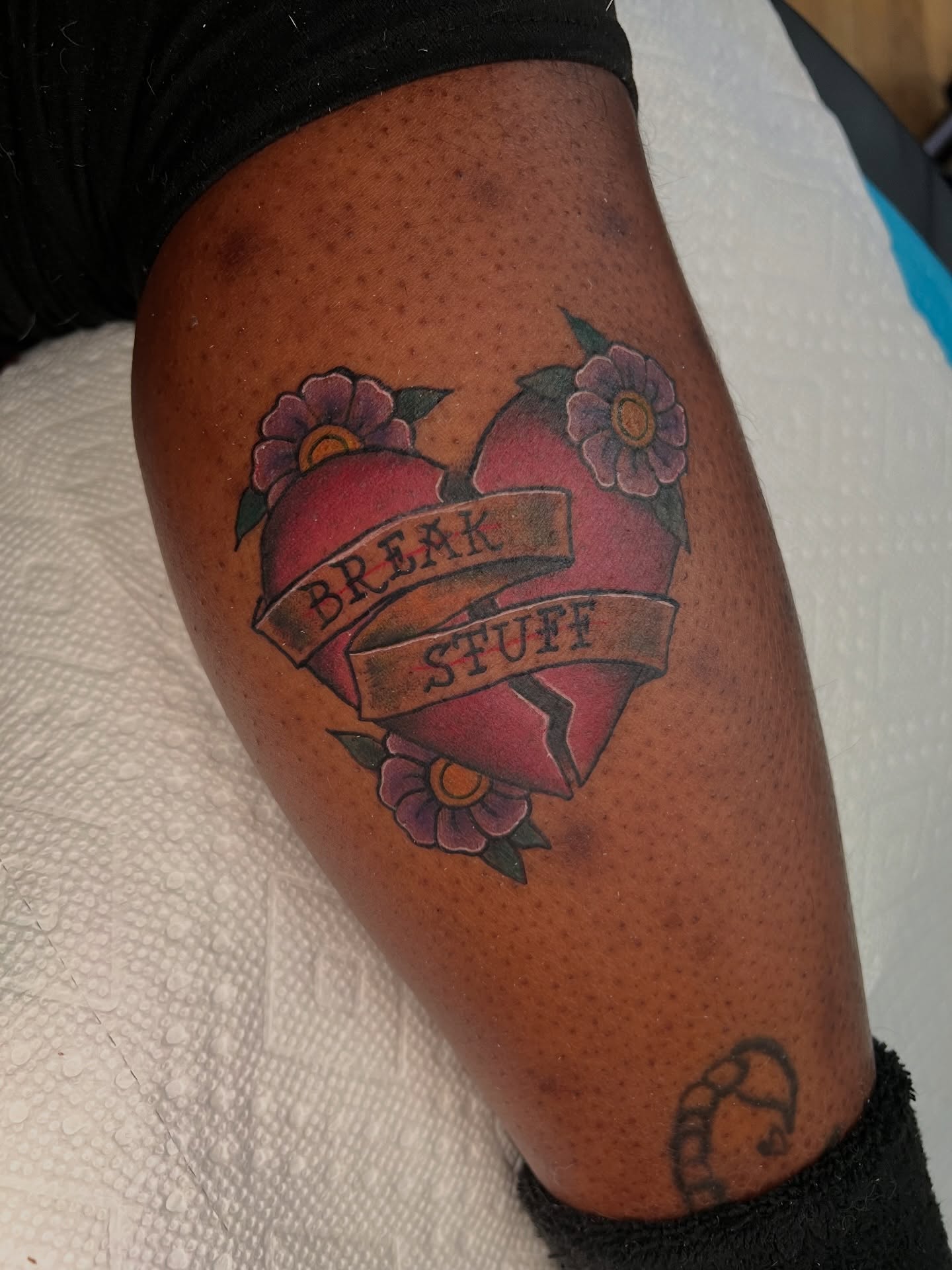 Broken heart with flowers American traditional tattoo on the thigh by Brandon Durbin