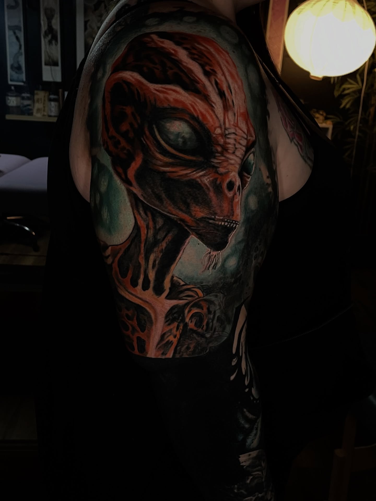 Alien head realism tattoo on the upper arm by Dean Rogers