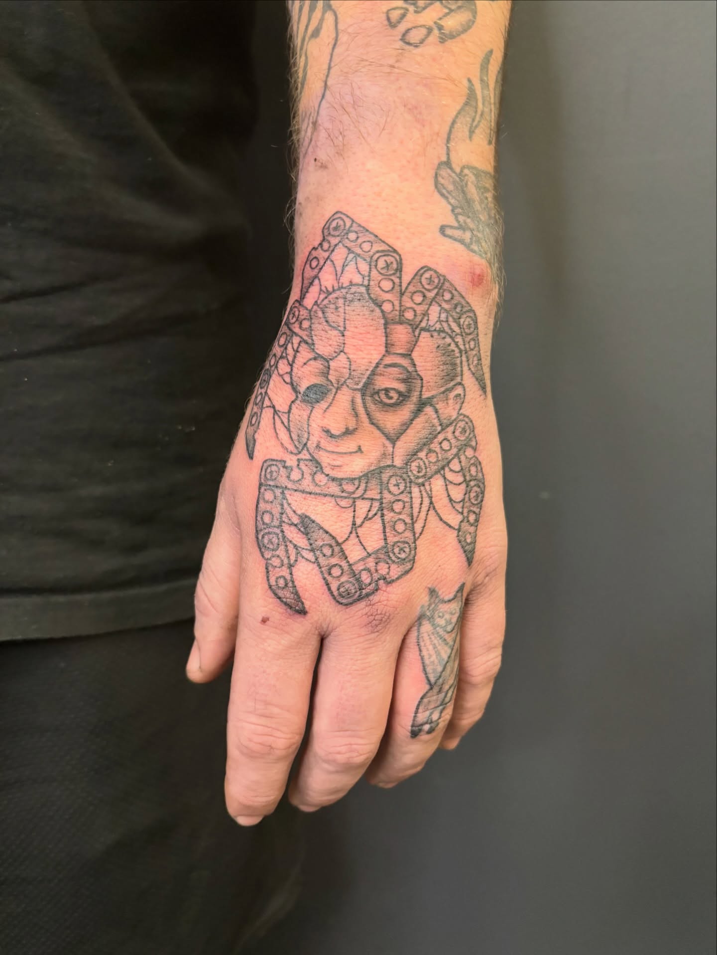 Jester black and grey tattoo on the hand by Noah Blum