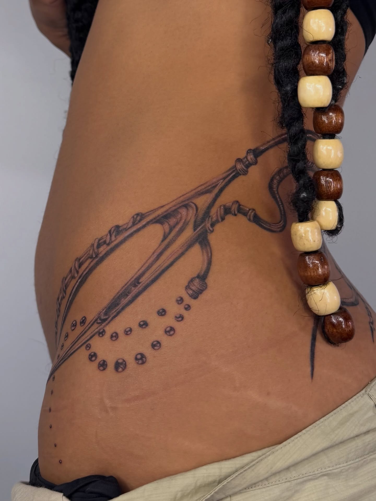 Arrow and beads dotwork tattoo on the thigh by Lauren ๐