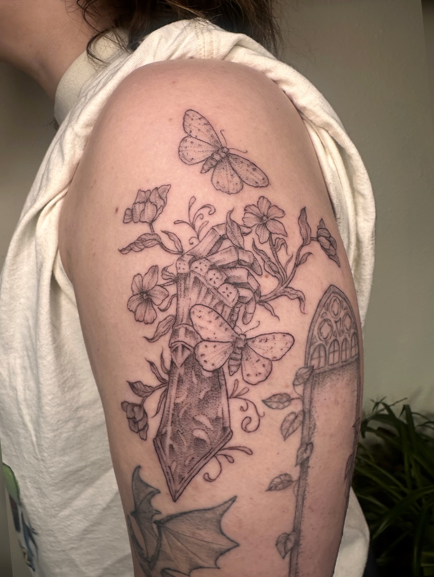 Butterfly and flowers black and grey tattoo on the shoulder by kenzie hunter